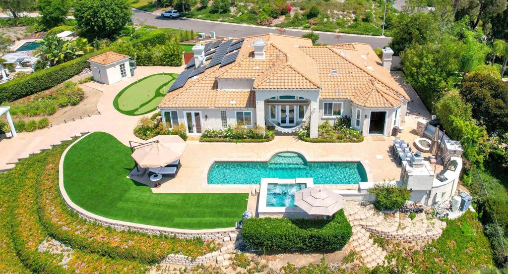 Welcome to this exquisite single-level home, where elegance meets comfort in every detail. Inside, you’ll discover a bright, inviting interior designed for both family life and sophisticated entertaining. This 4-bedroom, 3-bathroom residence impresses from the moment you step inside, with soaring vaulted ceilings, an open, light-filled layout, and 180-degree views of lush, landscaped grounds. The expansive living room, dining area, family room, and chef’s kitchen flow seamlessly together, featuring Anderson smoked chestnut wood flooring and custom cabinetry throughout—including a bespoke 180-bottle wine cabinet and built-in mini bar. The chef’s kitchen is a culinary dream, offering premium stainless steel appliances and an oversized 6’ x 10’ granite island. The serene master suite opens directly to the garden, creating a true indoor-outdoor retreat, complete with sitting area, fireplace, spacious dressing closet, and spa-style bath. Modern comforts include water softener system, smart toilet/bidets, solar panels, an EV charging station, and dual HVAC systems for personalized climate control. Step outside to your own resort-style oasis: a heated saltwater pool with new tile and pebble tech finish, oversized spa, custom outdoor kitchen with imported wood-fired pizza oven, bocce ball court, flagstone hardscape, orchard with lemon, lime, and orange trees, and a large gazebo for meditation or relaxation. Don’t miss the chance to own this exceptional property—where style, comfort, and convenience converge into the ultimate home retreat.