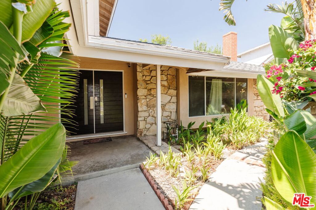 Set on a tranquil street in highly sought after Porter Ranch near top rated schools this spacious family home is ready to embrace generations to come. Behind the private front gate discover a lushly landscaped courtyard leading to striking double front doors. Step inside to the formal entry adorned with marble tile floors to reveal a generous living space with enough room for the whole family to gather around the fireplace or enjoy a movie night. The heart of the home is the open plan kitchen / dining area, which features a formal dining area with a custom light fixture as well as a grand kitchen peninsula adorned with stylish pendant lighting. Newer Torino dark wood cabinets pair effortlessly with stainless steel appliances, mosaic tile backsplash and sweeping stone countertops for timeless elegance and seemingly endless countertop space. The serene downstairs primary suite features ample closet space and a stylish en-suite bathroom complete with dual vanities, a sleek and impressive glass shower and modern oversized tile floors. Also downstairs is a versatile bonus room with access to the garage and laundry room, perfectly utilized as a game room or home office. Ascend the grand staircase to find three good sized bedrooms and a beautifully appointed bathroom with a shower/tub combo and designer lighting. The backyard features a covered patio ideal for entertaining, and the oversized garage provides abundant storage and parking options. Located in one of the most desirable neighborhoods in the Valley, this home is minutes from premier shopping, dining, entertainment, and freeway access, offering the ideal blend of suburban tranquility and city convenience.
