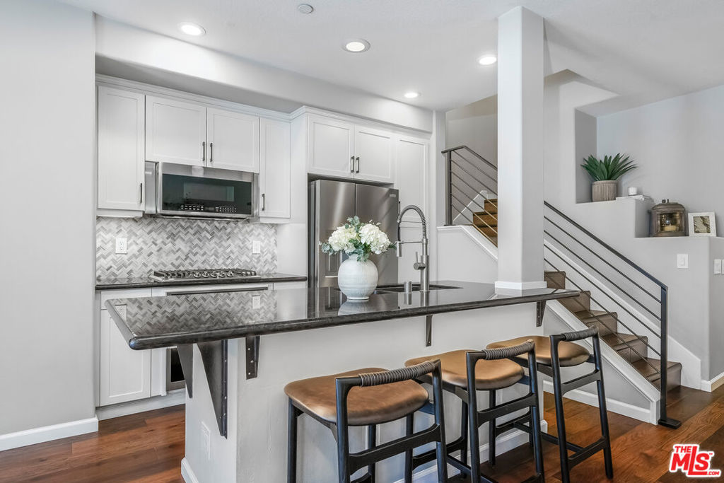 Welcome to this move-in-ready Fusion Plan A townhome, ideally located on the quiet south side of the community. This updated 2-bedroom, 2-bathroom unit features a light-filled open floor plan with modern finishes and thoughtful upgrades throughout. The kitchen is equipped with a brand-new 2025 Frigidaire Gallery Professional appliance package, granite countertops, white cabinetry, a newer designer backsplash, and a large center island with bar seating. The main level features a spacious bedroom, a full bathroom, and a laundry closet equipped with a stackable washer and dryer (included). Upstairs, the bright primary suite features a recently refreshed en-suite bathroom and great natural light. Additional features include a custom metal stair railing, wood flooring throughout, recessed LED lighting, high ceilings, central heating and A/C, and a Phantom retractable screen front door that opens to a private patio ideal for outdoor dining or entertaining. Smart home enhancements include Z-Wave/Zigbee smart dimmer switches and a RING doorbell. Parking includes a 1-car attached garage with storage, plus an additional assigned space (#16) and ample guest parking. Fusion is a gated community offering resort-style amenities with low HOA dues: pool, spa, basketball court, playground, fitness stations, pet relief areas, and well-maintained landscaping. Located just minutes from Manhattan Beach, El Segundo, LAX, and major freeways. Don't miss this rare opportunity to own a turnkey, upgraded townhome in one of the South Bay's most desirable communities!