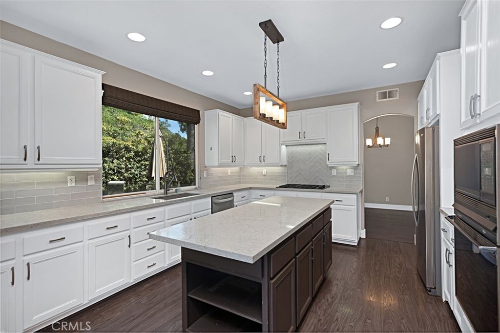 NEWLY AFFORDABLE - EXCEPTIONAL VALUE - enjoy all that prestigious Dove Canyon has to offer at 28 Lawnridge, a beautiful modern residence perched on a corner lot near the top of this coveted gated golf community in the foothills of Trabuco Canyon. This popular 4-bedroom floorplan (3 bedrooms and a large bonus room) has abundant natural light, an open layout, and is beautifully updated with luxurious surfaces and a modern neutral palette. As you enter, you'll find cathedral ceilings, elegant laminate flooring, an inviting living room, a dining room and family room with fireplace, guest bath and spacious laundry room. The kitchen has been tastefully remodeled with quartz countertops & custom tile backsplash, center island with a statement light fixture, stainless appliances, gas cooktop, wall oven and built-in microwave. Upstairs, a luxe primary suite awaits you with cathedral ceilings, ensuite bath with dual sinks, separate shower and soaking tub, and walk-in closet. Two large secondary bedrooms, an additional full bath, linen storage and an oversized bonus room complete the second floor layout. The entertainer's rear yard is ideal for year-round outdoor living, with a patio, firepit, low maintenance turf area, trees and more. An energy-saving whole house fan eases your energy usage, and the garage is equipped with a 240-volt Tesla charger that is compatible with all electric car models. The world-class amenities of Dove Canyon will be yours, with tennis, pickleball, a resort-style pool complex, 24-hour security and guarded gate, plus a variety of golf and social memberships available for the Dove Canyon golf club. Welcome home!