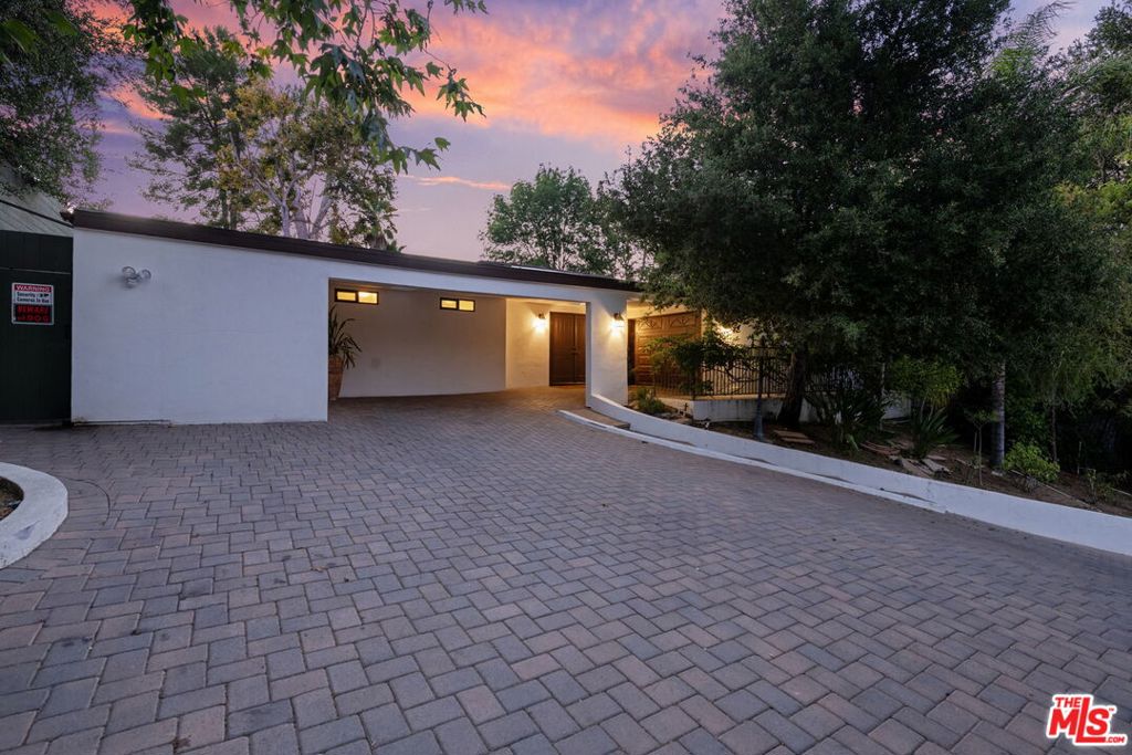 Welcome to Caritina Estates, a hidden mid-century gem and tranquil haven nestled in a secluded cul-de-sac just south of the boulevard in Tarzana. This exquisitely updated single-story residence commands attention with its 2,702 square feet of refined and elegant living space, set upon a sprawling 18,904 square foot lot. The home is masterfully designed to offer both comfort and contemporary luxury, featuring four spacious ensuite bedrooms, including two sumptuous primary suites. The residence's intelligently crafted layout harmonizes functionality with style, featuring warm hardwood floors that seamlessly guide you through the main living areas. In contrast, the kitchen and bathrooms are adorned with sophisticated ceramic and tile flooring, elevating the home's aesthetic appeal. At the heart of the home lies the Chef's Kitchen, a culinary dream equipped with a built-in refrigerator, sleek Ceaserstone countertops, and a modern backsplash and stainless steel appliances. Set amidst the serene backdrop of a canyon, this kitchen is perfectly poised for hosting lively gatherings by the pool or enjoying delightful alfresco dining amid the lush fruit trees. Step into the lush, private backyard, a true oasis crafted for both entertainment and serene retreats. The sparkling swimmer's pool beckons relaxation, while a dedicated BBQ area simplifies outdoor dining. Multiple outdoor living spaces offer idyllic settings for morning coffee or evening soirees. Beyond the immediate yard, the property extends into a generous orchard, home to 34 low-maintenance fruit trees. Here, one can harvest an array of fruits, from limes, lemons, and apples to diverse varieties of guava, pears, and other tropical delights, creating an environment that is as self-sustaining as it is enchanting. Adjacent to the main house, discover a versatile bonus room equipped with its own split AC system. This flexible space is perfect for a home office, yoga studio, creative haven, or simply additional storage. 4745 Caritina Drive represents a rare fusion of thoughtful design, abundant natural beauty, and contemporary amenities. It offers an unparalleled opportunity to bask in elegance, privacy, and a profound connection to nature, all within one of Tarzana's most sought-after neighborhoods.