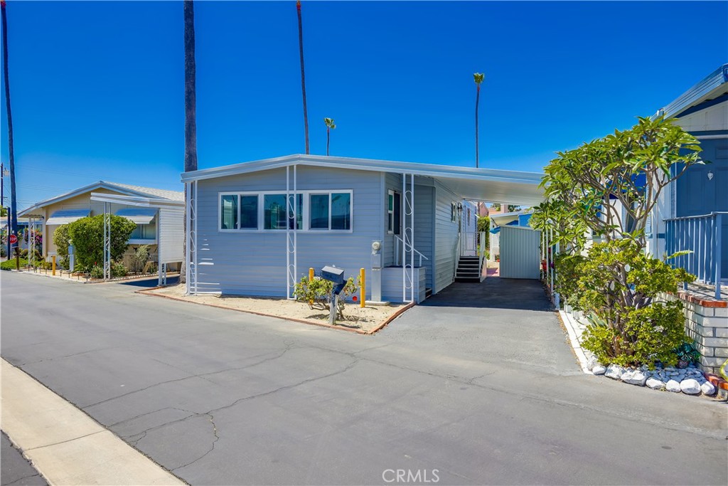 Welcome to your dream home in 55+ Community of Kona Kai — a cozy and functional 2-bedroom, 2-bath manufactured home offering comfortable living space in the heart of Santa Ana. This home has a bright sun porch with dual pane windows, perfect for relaxing or entertaining. Step inside to the main living area where you'll find a carpeted living room with classic wood-paneled walls and sliding glass doors that lead to the sun-drenched porch. The sun porch itself boasts carpeting, wood paneling, and a pitched ceiling that enhances the airy feel. Adjacent to the living room is the dining area, complete with a ceiling fan and built-in storage cabinet. The kitchen offers plenty of counter and cabinet space, white appliances, laundry area off the kitchen and access to the newly paved carport for convenient entry. The primary bedroom is carpeted with wood-paneled walls and includes built-in storage, a closet, and a private ensuite featuring a stand-up shower and single-sink vanity. The second bedroom mirrors the cozy feel of the first and is located near the second full bathroom, which includes a tub/shower combo and large vanity. Outside, the backyard is a blank canvas — ready to be transformed into your ideal outdoor retreat, garden, or play area. This community offers wonderful amenities including 2 swimming pools and a clubhouse. No HOA fees. Low land lease. Whether you're looking to personalize your space or settle into a well-laid-out home with great bones, this is a wonderful opportunity!