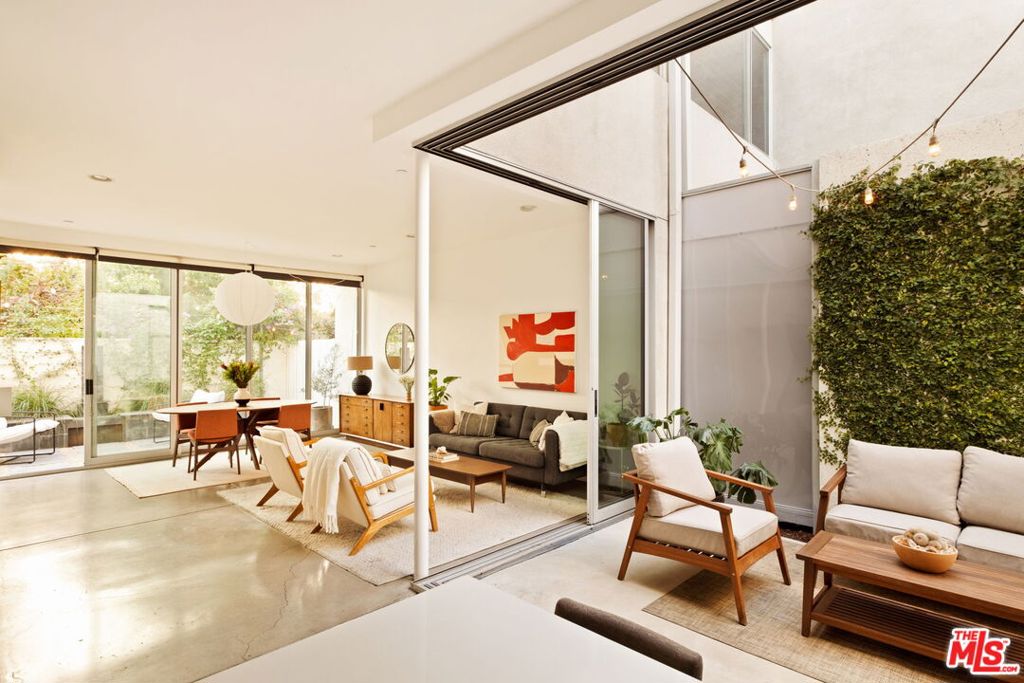 Tucked within the gated, sought-after Mews community of Atwater Village, this modern residence by acclaimed architects Corsini and Stark offers a rare blend of privacy, serenity, and refined indoor-outdoor living. Thoughtfully designed, the home welcomes you with a private courtyard that sets a calming tone from the moment you arrive. Inside, soaring ceilings and expansive glass sliders flood the space with natural light and seamlessly connect the interiors to the outdoors. With an open-concept layout, polished concrete floors run throughout the living and dining areas. The sleek kitchen features wood cabinetry, stainless steel appliances, and a large island. A well-positioned powder room adds convenience for guests. Just beyond, a second patio surrounded by lush landscaping flows directly from the main living space, effortlessly pulling the outdoors in. Upstairs, the primary suite is a true retreat with clerestory windows and breathtaking views of the surrounding hills. The en-suite bath features a dual vanity, soaking tub, and separate stand-up shower. Two additional bedrooms, a full bathroom, and a laundry closet round out the second floor. Additional features include solar panels, direct entry to the 2-car garage, and low-maintenance grounds. Located moments from Griffith Park, Frogtown, the LA River bike and pedestrian path, and favorite local spots like Proof Bakery, Cafecito Organico, Spina, and Dune. This home blends calm, curated design with the vibrancy of city living.