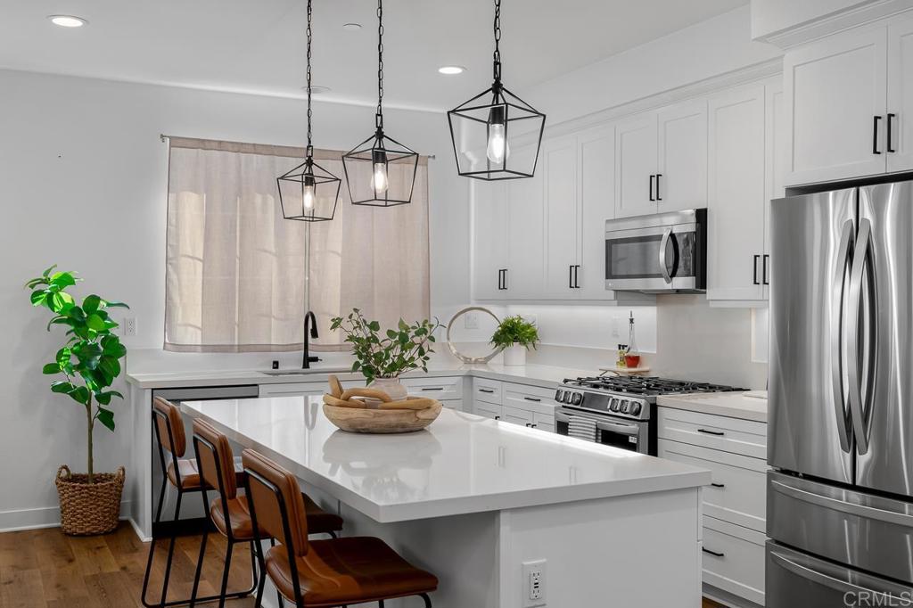 Seize the rare opportunity to own this 2024-built luxury townhome showcasing nearly $45,000 in premium designer upgrades! Offering 3 bedrooms, 3 bathrooms, and 1,461 sq. ft. of beautifully curated living space, this home blends modern sophistication with everyday comfort. The open-concept layout is drenched in natural light and showcases elegant flooring, recessed lighting, and sophisticated designer touches throughout. At the heart of the home, the chef-inspired kitchen takes center stage with an oversized island with breakfast counter seating for four, sleek quartz countertops, high-end stainless steel appliances, a spacious pantry, and stylish pendant lighting. A dedicated dining nook offers the perfect spot for gatherings, while the seamless flow into the expansive living area creates an inviting space ideal for both entertaining and everyday living. Upstairs, the primary suite boasts a spa-like bath with dual vanities and a generous walk-in closet. Two additional bedrooms offer flexibility for guests, a home office, or a growing household, while a convenient upstairs laundry adds ease to daily living. The versatile ground-level entry space can be reimagined as a stylish home office or a contemporary mudroom. This smart, energy-efficient home features solar panels, dual-pane windows, a tankless water heater, a whole house fan, and a finished 2-car garage with epoxy flooring and overhead storage. Residents enjoy access to thoughtfully designed community amenities including a greenbelt, fire pit, BBQs, picnic tables, and a kid-and-pet-friendly play area. Perfectly located in desirable South Escondido, this home offers quick access to the San Diego Zoo Safari Park, Stone Brewing World Gardens, Lake Hodges, Orfila Vineyard & Winery, North County Mall, and all the restaurants, shops and outdoor hot spots that make Escondido such a wonderful place to call home. Close proximity to major freeways connects you with the best San Diego County has to offer. Move-in ready and meticulously upgraded, this townhome delivers the ultimate combination of luxury, convenience, and lifestyle.