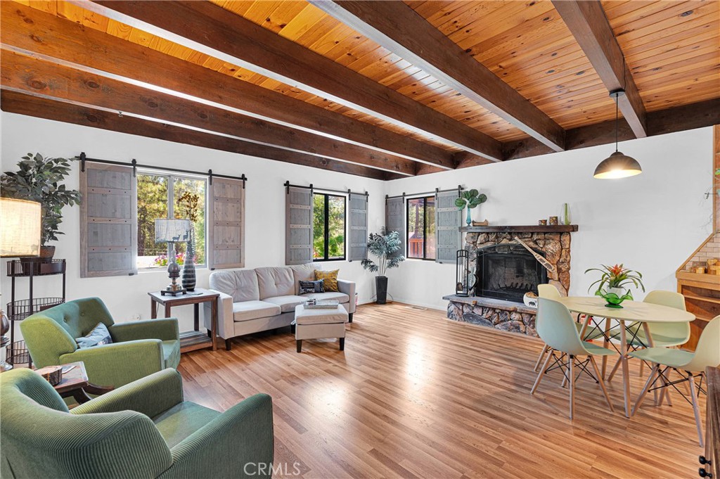 Welcome home to your Wrightwood barndominium! With a unique gambrel-roof, it is brimming with rustic character and modern comforts. In the charming mountain community of Wrightwood. Village is within walking distance. This home has an expansive wrap around deck, patio area and perched higher above the street for privacy and stunning mountain views. This property invites you to relax and unwind on its expansive custom wrap around deck. This 2 story home features 2 bedrooms, one and a half baths., and a versatile bonus room downstairs- perfect for a third bedroom, home office, or home school space. Enter into a spacious light living room with a beautiful beamed and knotty pine high ceiling. Custom barn door style sliding shutters. On those wonderful winter nights, light up the natural rock wood burning fire place and gather around. Waterproof wood style flooring. The open concept kitchen is a chef's dream with Birchwood cabinets with custom hardware. Butcher block counters with tile back splash. Tons of storage and built in shelving. Two movable butcher block islands on wheels with storage, Built in pantry with pull out drawers.Recessed lighting. Laundry area down hall way with bathroom across with Travertine tile work. A glass door leads to the outside. . Slider doors lead onto the deck. Upstairs there are two bedrooms and a full spacious remodeled bathroom with custom tile counters which extends all the way around the bath tub and shower. with two shower heads. Front bedroom os very spacious with a large closet. Bed room on other side has a lighted closet. . Step out onto your custom wrap around deck and relax with a great sitting area. Think of dining Al Fresco on our beautiful summer nights. An 8 X 10 shed for extra storage on the back deck. Or maybe a potential play room. Property is cross fenced Plenty of parking. Basement storage. This home is turn key and ready for you to move in. This more than a home a home -- Come experience the peace, privacy, and charm of Wrightwood living. Come enjoy all the mountain activities in all four seasons. Mt. High is right up the road. Become a member of the Wrightwood Country Club.. There is a waiting list . Wrightwood Elementary is right down the road. Concrete septic tank.