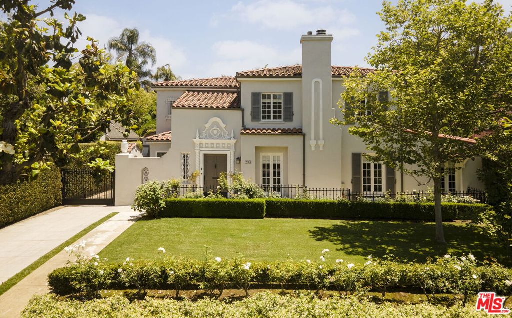 This exceptional Mediterranean Revival home is nestled in the heart of Windsor Square, offering privacy and charm with lush landscaping and a spacious grassy front yard. A formal entryway leads to a sweeping staircase that opens into the grand living room, featuring original crown molding, hardwood floors, French doors, and fireplace. A separate step-down office is thoughtfully designed with custom built-in shelving. The elegant formal dining room flows seamlessly into the inviting family room, which boasts a fireplace, custom shelving, and expansive wall-to-wall glass doors with electronic shades, offering stunning views of the large backyard. The eat-in kitchen is a chef's dream, with marble countertops, center island, Viking Range, Sub-Zero appliances and temperature controlled wine storage. Upstairs, you'll find three spacious en-suite bedrooms, including a luxurious primary suite complete with a spa-like bathroom, dual vanities, a large shower, a separate soaking tub, and water closet. The custom walk-in closet features inset lighting and the feel of a high-end showroom. For convenience, both upstairs and downstairs are equipped with washer/dryer units. The beautifully landscaped backyard features a covered living space with built-in heaters, fridge, BBQ and a sparkling saltwater pool with a tranquil water feature. There is a separate en-suite guest room. The gated driveway leads to a two-car garage with additional storage. Located just blocks from Larchmont Village. Would make a wonderful place to call home!