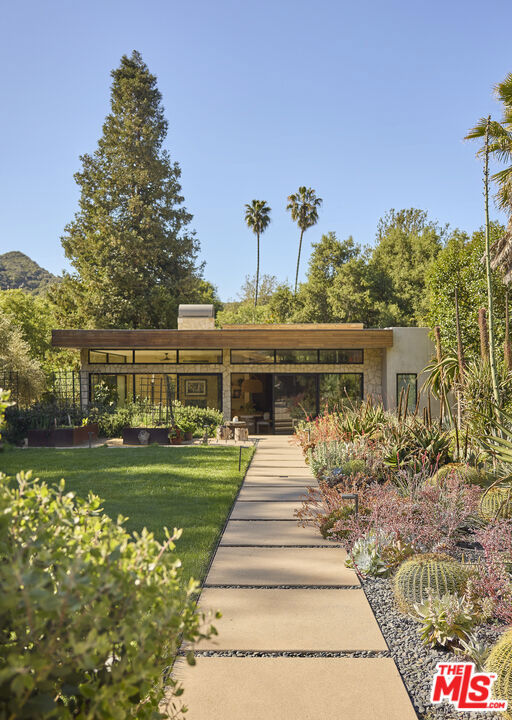 Nestled in the serene beauty of Topanga, CA, 1418 Bonnell Dr offers a perfect blend of luxury and tranquility. Designed by the acclaimed architecture firm Electric Bowery, this stunning newer-construction home features 4 bedrooms and 4 bathrooms, thoughtfully crafted to harmonize with its natural surroundings. Set on an expansive lot, the property provides a rare sense of privacy and space. Step inside to discover an open and airy floor plan with a warm modern design where high ceilings, large windows and sliding glass doors fill the space with natural light and welcome a true indoor/outdoor lifestyle. The spacious public areas flow seamlessly from the living room through the gourmet kitchen and into the family room and gym. The private rooms are introduced through a thoughtful hallway where each of the four bedrooms are carefully designed, with the primary suite featuring a luxurious bathroom and access to a private outdoor patio. Outside, the true magic of this property unfolds. The beautifully landscaped grounds curated by Campion Walker are surrounded by mature trees and lush greenery, creating a picturesque setting. Enjoy leisurely days by the sparkling pool or unwind in the charming pool house, a perfect spot for relaxation or hosting guests. Located in a highly desirable neighborhood steps away from the lovely Bonnell Park this home is a true sanctuary, offering the best of both worlds -- tranquil escape amidst nature, yet close to all the amenities Topanga has to offer. Experience the epitome of California living in this exceptional home.