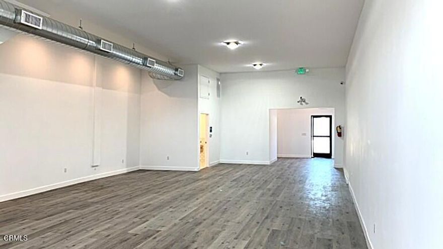 This updated street-level commercial space, part of a multi-use building, is available for immediate occupancy. There is a customer/client reception area, a waiting room, and a small reception office space behind the room with sliding windows. A large open floor plan, approx. 700 sq. ft., with wood laminate flooring, and a rear room that can be used as a media room, break room area, and more. Industrial ducting provides central air and heat amongst the high ceilings. There is a rear entrance door accessible from a rear parking area, accessible behind a motorized sliding gate off the rear alley. This unit comes with two off-street parking spaces. There is a storage area underneath a stairway inside as well. A spacious ADA-compliant bathroom with four-foot-high tile walls all around. Additional electrical outlets along both sides of the walls. This lease amount is inclusive of all NNN expenses. Wired for security cameras and card access..