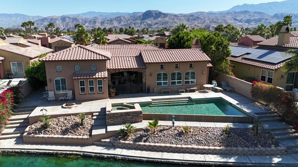 Enjoy desert living at its finest in the unique gated 9-acre lake community of Santo Tomas. This stunning waterfront home embodies all the elements you could possibly desire in a desert retreat! This rarely offered model perfect home has 4 bedrooms, 4.5 bathrooms, including an attached guest casita, and many designer upgrades. The curb appeal will immediately impress you, including a gated courtyard then enter the homes foyer that opens to the great room and looks out to the heart of the home; a large central covered patio for you to relax, entertain or even enjoy alfresco dining. The stylish oversized island kitchen features granite counter tops, professional stainless appliances and flows into the dining area & family room creating the perfect space for entertaining and casual living. The master suite offers access to the covered patio and overlooks the lake. The yard is sure to impress with an infinity pebble-tec pool & raised spa, cascading waterfall, conversation fire pit all with striking lake front views. This is the home you have been dreaming about!