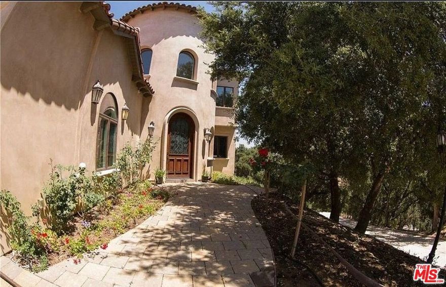 Privately situated on over one acre in a sought-after Calabasas community, this Mediterranean Contemporary residence offers nearly 6,000 square feet of living space. Built in 2013, the home features 5 bedrooms and 6.5 bathrooms with a thoughtfully designed floor plan.Interior highlights include a two-story entry, hardwood flooring, formal living and family rooms with fireplaces, dining room, bonus room, loft, and a wet bar. The primary suite offers a fireplace, walk-in closet, and full bathroom. The kitchen is designed for functionality with custom cabinetry, a large center island, pantry, stainless steel Viking appliances, and travertine finishes.The property is equipped with a security system and provides multiple spaces for entertaining. The backyard includes a built-in barbecue, mature fruit trees, waterfalls, fire pit, and a custom stage with professional audio/video wiring. Outdoor areas are designed for gatherings, performances, and recreation. Proprty is set high on a private hilltop, this estate is accessed through its own gated drive, offering both privacy and security. As you enter, a separate motor court provides parking for 8-10 vehicles. The kitchen is equipped with top-of-the-line Wolf appliances. If leased furnished, the home features hand-carved, custom designer antique furniture of exceptional quality.