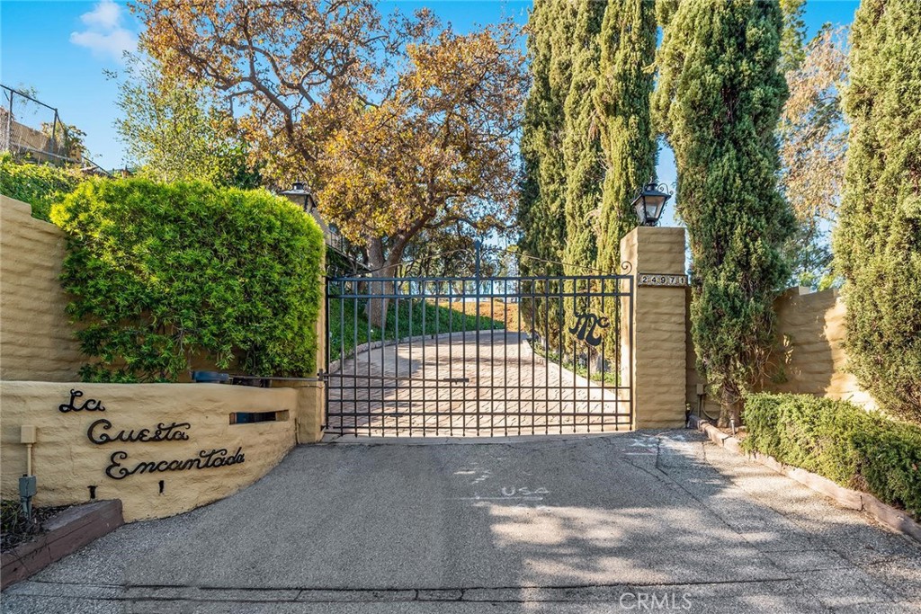 This wonderfully private home affords panoramic city lights and pastoral views and is sited behind its own private gate. Upon entry, the main level of the home offers a living room, dining room, and spacious family room that opens the kitchen with newer appliances, plus there are two downstairs bedrooms, a laundry room and direct access to the three car garage. The primary suite is on the second level with an oversized walk in closet, remodeled bath, big sitting balcony, and views of the valley floor. There are an additional three bedrooms upstairs and a shared hallway bathroom. The home also features big picture windows, wood floors, and an open floor plan. The grounds include a big pool, spa, covered patio, sunning patio, and forever views.