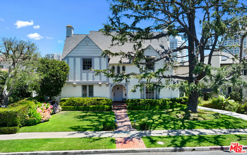 A revival of almost a century old, story-book Country English in prime Little Holmby. Framed by manicured gardens and a regal frontage, this distinguished 1930s remodeled Masterpiece of Timeless Elegance designed by Percy Parke Lewis (Westwood's Village Theater, St. Albans Church, Chateau Colline, El Encanto Apartments...) offers a rare blend of architectural heritage and modern refinement in one of Westwood's most coveted enclaves. Inside, natural light pours through original beveled windows, illuminating polished dark hardwood floors, soaring ceilings, and exquisite millwork. The formal living room, anchored by a classic fireplace, opens to a sunroom that captures the serenity of the lush grounds beyond. A bespoke chef's kitchen, centered around a La Cornue range, is both a culinary showpiece and a warm gathering space, complete with a built-in banquette and custom cabinetry. The elegant dining room opens to a private patio, ideal for al fresco entertaining beneath the stars. Upstairs, the primary suite is a tranquil retreat with a spa-like bath, while two additional bedrooms share a beautifully updated bathroom. A separate guest suite above the garage offers privacy and flexibility for visitors, creative work, or extended stays. Additional highlights include a richly paneled library/den, integrated AV and security systems, and a garden sanctuary with a multitude of herbs, citrus and fruit trees, all set behind hedged privacy on a premier street. This is not just a home it's a legacy property, moments from Holmby Park, UCLA, Mathias Botanical Gardens, upcoming metro stop and the cultural heart of the Westside.