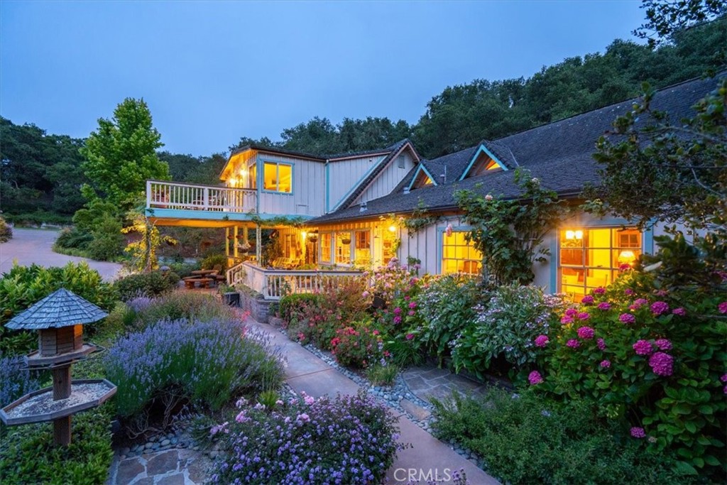 Welcome to a serene, secluded sanctuary surrounded by natural beauty. Nestled behind a private gate at the end of Oak Haven Lane, this 4 bedroom, 3 bathroom home on 1.14 acre offers gorgeous views of the surrounding hills and peaceful, Zen like setting. The charming, detached cottage is 1 bed/1 bath (not included in sq footage or bedroom/bath count) features A/C, Trex deck, and views of the gardens.
Thoughtfully landscaped and lovingly curated over the past 20 years, the lush, oak-studded grounds offer a meditative retreat feel with a calming koi pond and waterfall, fairy and butterfly gardens, meandering meditation paths, multiple flagstone walkways, decks, raised beds, fruit trees including avocado, orange, and apple, sitting areas, bird feeding stations and all of it privately enclosed by 8-foot deer fencing.
With stunning natural pine interiors and abundant windows that bring in natural light and breathtaking views from every room, this is Central Coast living at its finest. The kitchen boasts extensive counter and cabinet space, premium DCS cooktop with griddle, a separate warming drawer, walk in pantry, breakfast bar, under-sink R/O system and inspiring views of the hills and gardens below. Separate dining room offers plenty of space for memorable gatherings. The family room creates an ambiance of comfort and relaxation. The open living room features soaring wood-beamed ceilings, a grand fireplace, and panoramic garden views.
Upstairs, the oversized primary suite offers a walk-in closet, a private seating area, dual sinks, jetted tub, walk-in shower, and a spacious private balcony overlooking the gorgeous landscape and surrounding hills. Three additional bedrooms are thoughtfully positioned for guests or family.
Enjoy the large covered front porch surrounded by lush greenery or relax on the sunny deck that overlooks multiple gardens. Lovingly designed to be beautiful in every season.
From the Cottage, a flagstone path leads to a rustic garden shed and steps down to the koi pond and butterfly garden. Up above, is an area for additional parking including a 2-car carport. Next to the carport is a large workshop with its own deck and seating area and down below is a large shed for additional storage.
This is the ultimate private escape, yet just minutes from the Village of Arroyo Grande and the scenic back way into San Luis Obispo.
