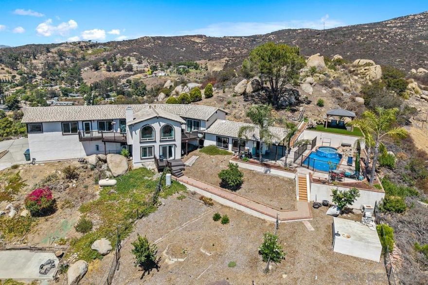 Granite Hills entertainer’s oasis! This 1.25-acre estate offers panoramic views, 4 bedrooms, 4 baths, and abundant living space. Garages for 5 vehicles, RV parking, and owned solar add convenience and value. Inside, rich wood floors flow through the great room to walls of windows framing forever views. The gourmet kitchen features dramatic granite counters, Viking appliances, a 60" six-burner range, and 48" Sub-Zero refrigerator. The formal dining area doubles as a game room, while the sunken living room and two balconies create ideal gathering spaces. The primary suite showcases sweeping vistas, a walk-in closet, and spa bath with dual vanities, separate shower, and Jacuzzi tub. Downstairs includes 2 bedrooms, 2 full baths, laundry room, bonus space, and family area. Detached garage converted into a 2 bed 1 bath ADU with Kitchen. Great value for extended family or rental. Resort-style living with privacy, parking, and panoramic views—welcome home!  Welcome to your private Granite Hills retreat—an entertainer’s dream with sweeping panoramic vistas! Situated on 1.25 acres, this estate showcases 3+ bedrooms, 4 baths, expansive indoor and outdoor living spaces, and garage parking for up to five vehicles. Additional features include RV parking, owned solar, and more. Step through the formal entry and be greeted by rich wood floors leading into the great room, where endless views set the tone. Across from the formal dining area—currently used as a game room—you’ll find the grand gourmet kitchen, highlighted by striking granite counters and a full suite of Viking appliances, including a 60-inch six-burner range and a 48-inch Sub-Zero refrigerator. Gather at the oversized eat-up bar or relax in the sunken living room while enjoying the views, whether from indoors with central cooling or out on one of two private balconies. The primary suite offers breathtaking vistas, a generous walk-in closet, and a spa-inspired bath featuring dual vanities, a separate shower, and a two-person Jacuzzi tub. Downstairs, two additional bedrooms and two full baths are complemented by a laundry room, bonus space, and a family area—perfect for flexible living.