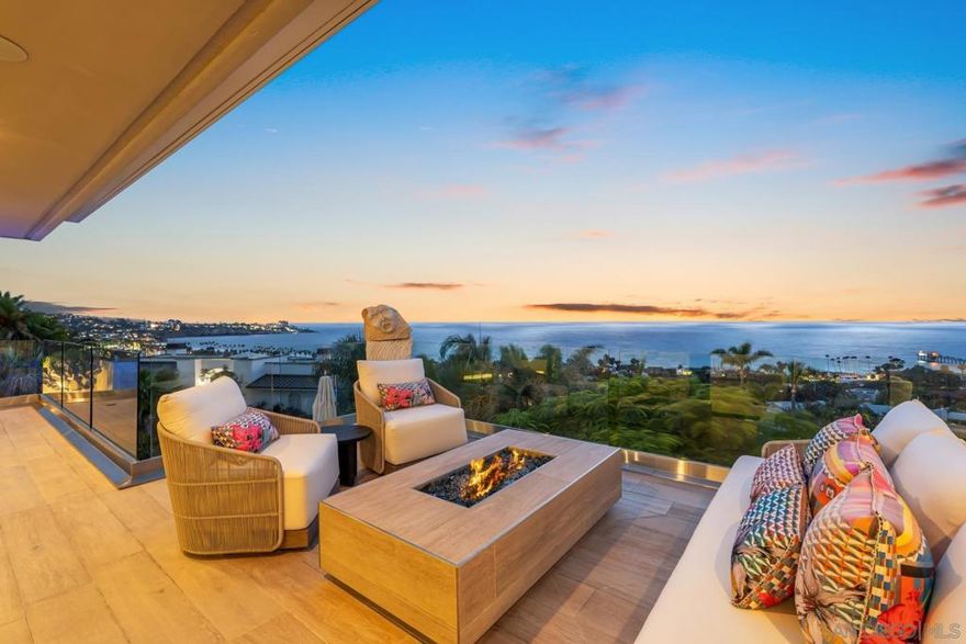 Set above iconic La Jolla Shores Beach, providing panoramic views of the ocean, Scripps Pier, and La Jolla Cove, this extraordinary estate offers a rare blend of privacy, scale, and effortless sophistication. Tucked on a 0.49-acre parcel within the gated Montoro enclave, the 8,927 sq ft residence has been completely reimagined for refined luxury and seamless indoor-outdoor flow. The home features 4 bedrooms, 4 full and 4 half baths, an office, gym, media room, wine cellar, and garage parking for 6 vehicles. Vast walls of glass and floor-to-ceiling sliding doors immerse the interiors in breathtaking coastal scenery and abundant natural light. Expansive living areas and a chef’s kitchen open to a spectacular view terrace—ideal for dining al fresco or soaking in the sunset. The redefined primary wing is a true retreat, with a fireplace, dual sitting rooms, wraparound view deck, two boutique-style walk-in closets, and dual spa-inspired baths with steam showers—one with a spa tub. The lower-level hosts 3 secondary bedrooms, an office, gym with sauna, media lounge with wet bar, and wine cellar. Outdoors, a setting of beauty and seclusion unfolds from a sprawling patio with pool and spa, outdoor kitchen, ocean-facing decks on each level, and a flat turfed yard bordered by lush landscaping. Car enthusiasts will appreciate a 2-car attached garage plus an oversized 4-car detached garage. A Crestron system integrates lighting, climate, audio/visual & security cameras. Montoro amenities include a pool, spa, and 2 tennis courts—just minutes from the beach, UCSD, dining, and The Village.