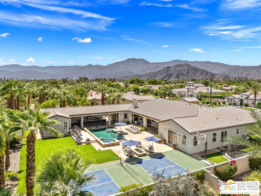 MADISON ESTATES luxury living! This impressive 5-bedroom, 5.5-bath residence spanning over 5,000 square feet offers 5 ensuite bedrooms with a detached 2-room casita in the mix. Open concept living with tall ceilings blends seamlessly to an expansive outdoor entertaining space designed for year-round enjoyment. A fabulous covered patio with fireplace, sparkling pool and spa, outdoor shower, and multiple dining and lounging areas are complemented by a huge outdoor kitchen with large island with built-in fire pit and dual TVs framing the space. Additional fire features frame the pool, misters keep things cool, and the view at night is spectacular. A private pickleball court completes the resort-style setting. Inside, the kitchen is the heart of the home, anchored by a substantial island with impressive seating capacity for gathering and entertaining. Custom cabinetry, a 5-burner gas cooktop, dual ovens, and refined finishes set the tone. The living area off the kitchen flows beautifully for entertaining, complemented by a formal dining room. Ensuite bedrooms enjoy a nice separation, with two lining each wing of the home, and the casita offering even more flexibility. Herringbone tile, custom woodwork, tall ceilings, and lovely finishes throughout add sophistication. The primary retreat opens to the pool area and features a private sitting area, spa-like bath with soaking tub and walk-in shower, and an impressive walk-in closet. Separate garages accommodate three cars in total. Madison Estates is a private gated enclave of just 55 homes on half-acre lots. Residents enjoy privacy, scale, and prestige along with proximity to the Empire Polo Club, PGA West, The Madison Club, and the valley's world-class golf, dining, and entertainment, all with low HOA fees and land you own. Enjoy it all!