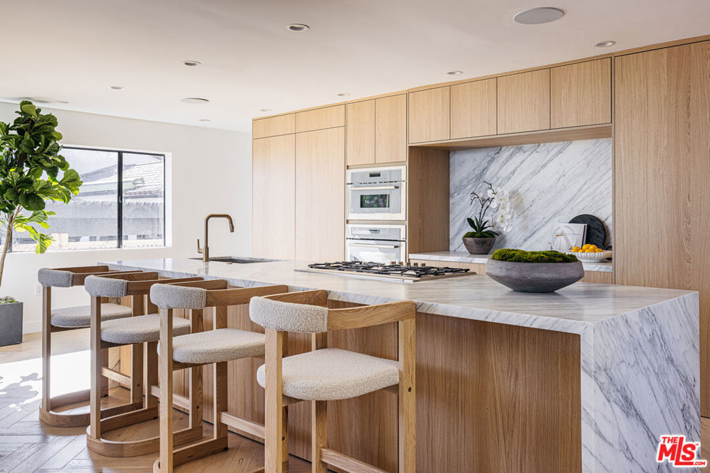 A fully renovated Hollywood Hills retreat with rare, sweeping 270 views from Downtown to Century City. This 4-bedroom, 4-bathroom home spans over 4,000 square feet, blending high-impact design with comfort and functionality. Nearly every room captures uninterrupted city views, while the multi-level layout offers both expansive entertaining areas and serene private spaces. Enter through a custom pivot door and be greeted by a dramatic architectural lighting feature that sets the tone for the home's striking design. A floating oak staircase leads to the double-height living area, where herringbone oak floors and retractable glass walls open to a wraparound balcony and panoramic skyline vistas. The dining area flows seamlessly into a custom marble kitchen, complete with Thermador appliances and a hidden walk-in pantry tucked behind bespoke oak cabinetry. A stylish powder room with an integrated Calacatta Viola vanity completes the main floor. On the second level, a custom sauna sits just outside the luxurious primary suite, which features a private balcony, spa-style bathroom with soaking tub and marble shower, and a spacious walk-in closet. Two additional bedrooms, a full bathroom, and a laundry area complete this floor. The lower level includes a separately accessed ADU with both interior and private exterior entrances featuring its own wet bar, full bathroom, and wraparound windows. It's a flexible space ideal for a gym, creative studio, guest suite, or rental opportunity. Down below, a rare turf yard offers even more flexibility with room for a cold plunge, small garden (including a lemon tree), or cozy outdoor lounge area. A two-car garage completes the property. Quiet, private, and perfectly positioned just minutes from Sunset, West Hollywood, and Beverly Hills. 7866 Fareholm is a rare find that offers the best of both worlds: breathtaking views and everyday convenience.