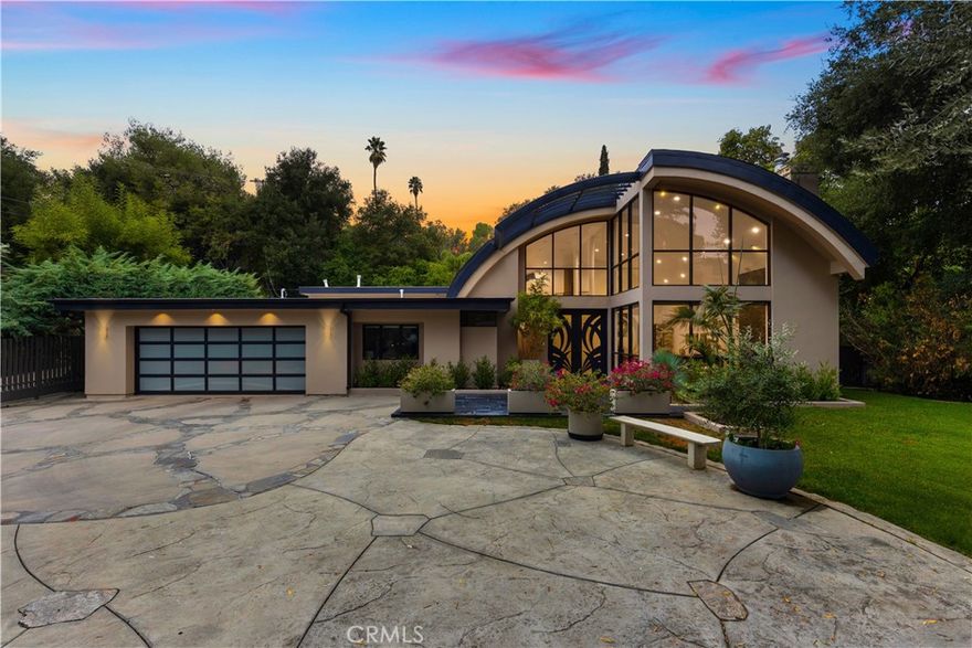 Nestled in the hills of Tarzana on a sprawling 18,000+ sf gated lot, this custom-built residence showcases striking architectural elements and is strategically set back from the street to create a private retreat. Enter through bespoke double doors into a grand foyer that flows seamlessly into the spacious formal living and dining room. Lofty 20 ft ceilings and expansive walls of glass that stretch from floor to ceiling flood the space with warm natural light, making the space feel bright and airy. Through the butler’s pantry lies a gourmet chef’s kitchen, outfitted with commercial-grade Viking appliances, a walk-in pantry and center island with an integrated dining table. A sliding glass door in the family room leads out to the secluded backyard sanctuary, which is surrounded by mature landscaping and boasts a heated pool and spa. There are four generously sized ensuite bedrooms spread throughout the home, each with a walk-in closet. The expansive primary suite features a versatile bonus space, private balcony, custom walk-in closet and sumptuous bathroom, complete with a soaking tub, steam shower, double vanity and separate makeup vanity. Additional highlights include a dedicated laundry room, security system, countless upgrades (newer roof, wide plank oak floors, dual pane windows, built-in speakers and so much more), a two-car garage with an EV charger and gated driveway with ample space to park multiple vehicles. Located south of the Boulevard in a top-rated school district, this property is just moments away from everything the Valley has to offer.