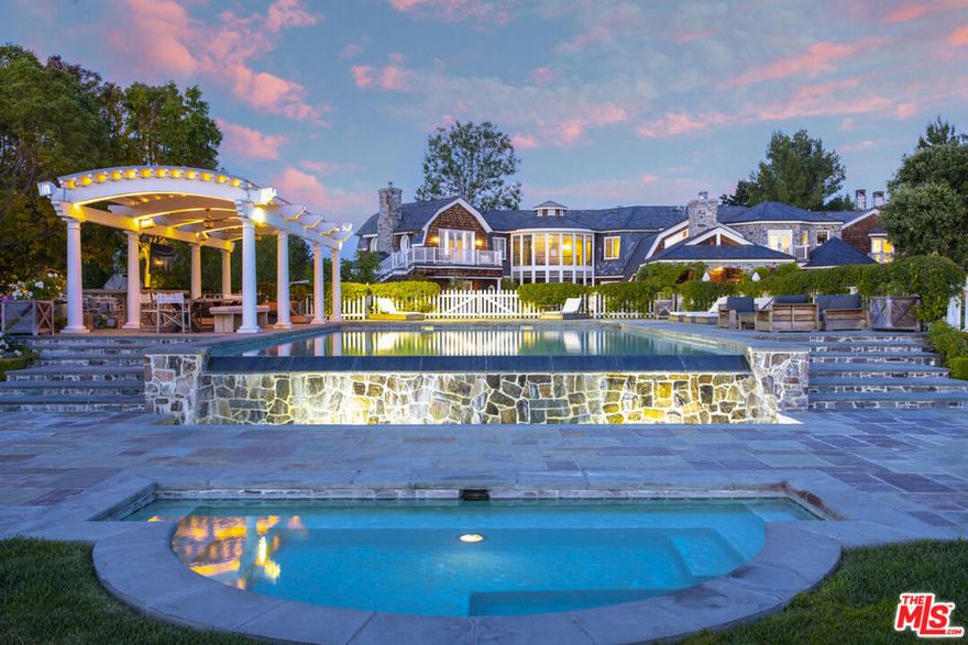 Nestled within the highly sought-after guard-gated community of Hidden Hills, this private retreat, tucked away at the end of an intimate cul-de-sac, spans approximately 13,274 square feet and rests on 2.25-acres, offering mesmerizing city lights and mountain views that will leave you breathless. As you step inside, you'll immediately be struck by the grandeur of this home. Featured in the esteemed pages of Architectural Digest, every detail has been meticulously crafted to create a truly captivating living experience. Awe-inspiring features abound, including eight spacious en-suite bedrooms with beautifully appointed baths, a guest house complete with a kitchenette, and an intricately paneled study featuring a warm fireplace. The exquisitely accented formal dining room sets the stage for unforgettable dinner parties, while the dramatic foyer boasts a stunning spiral staircase and floor to ceiling windows that flood the space with natural light. The heart of this home lies in its state-of-the-art chef's kitchen, where culinary dreams come to life. Showcasing top-of-the-line Wolf appliances, a walk-in pantry, a central island, and a breakfast nook. The family room is a true sanctuary, with oversized sliding barn doors, a fireplace adorned with reclaimed brick, and beamed vaulted ceilings that create an inviting & relaxing ambiance. Retreat to the luxurious primary suite, featuring a comfortable sitting area, a stone fireplace, and an expansive his-and-hers walk-in closet, that exudes grandeur. The expansive rear grounds are a true outdoor paradise, where relaxation and entertainment seamlessly blend. Rolling lawns, a sparkling pool with a separate shallow pool, a rejuvenating spa, a BBQ island, and convenient amenities like an outdoor shower and bathroom create an idyllic setting for enjoying the Southern California lifestyle. Here you can immerse yourself in the breathtaking vistas that stretch beyond, making every moment spent outdoors a feast for the senses. This home offers an unrivaled opportunity to experience the epitome of upscale living in one of the most exclusive communities. Don't miss your chance to own this remarkable property and create a lifetime of cherished memories.