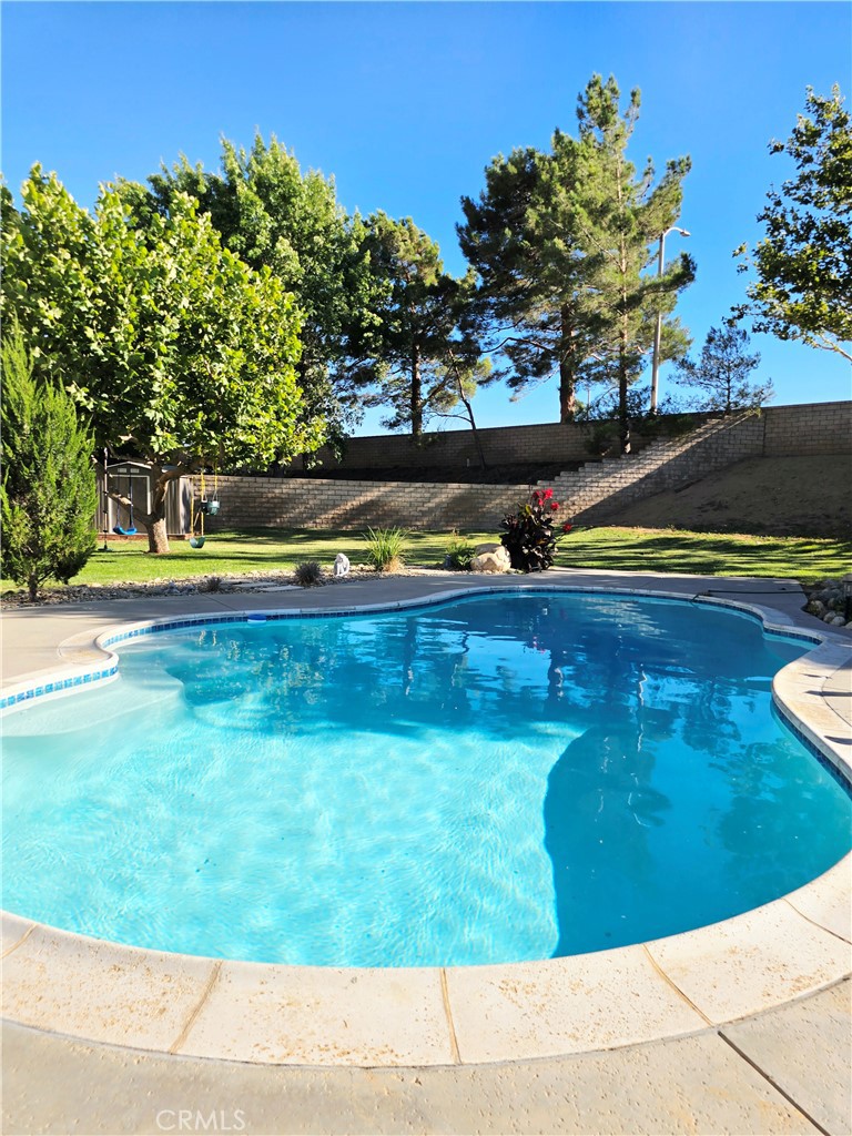Welcome to your slice of paradise! This 4-bedroom, 3-bathroom home that sits on a prime location of West Palmdale with great schools in the area and, just a quick 5-minutes from good restaurants, convenient stores, and 10 minutes from the Palmdale Mall.
This stunning two-story house has an open concept layout with amazing high ceiling, modern finishes, and an abundance of natural light. The updated kitchen features stainless steel appliances, a large and spacious island, granite countertops, good amount of cabinet for storage, also a pantry area, and seamlessly flows into the living and dining areas—ideal for entertaining. Relax in the spacious primary suite featuring a see-through fireplace with a lounge area to enjoy a nice relaxing time, and direct access to the lovely balcony overlooking the pool area. Also the Master bedroom has a beautiful bathroom with a double sink, a tub, and a standing shower with glass doors and don' t forget the added storage offered by the Master walk-in closet or the ample and spacious closets featured in each of the 3 other bedrooms. One bedroom and one full bathroom on the first story and 3 bedrooms upstairs including the master bedroom.
This home offers a SOLAR SYSTEM which is debt free and paid off and a three car garage, double panel windows, central AC and a convenient laundry room on the first floor.
Enjoy many days with family on this half of acre landscaped patio with a resort style private in-ground sparkling pool. A true entertainers back yard. Truly relaxing.
DO NOT MISS OUT on this opportunity to live in Paradise Pool House on West Palmdale!