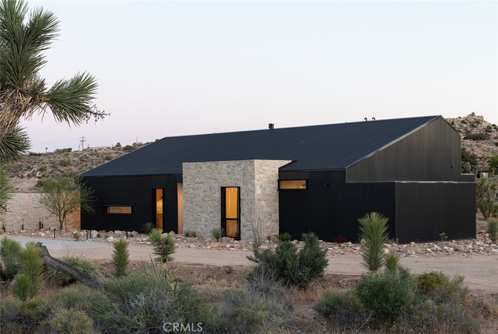 Picture-perfect and income producing, this 3 bedroom, 2 bathroom modern luxury home (built in 2023) is being offered fully furnished and turn-key. Currently operating as a high-performing short-term rental, the property offers both a dream desert lifestyle and the opportunity for a strong income-producing investment with potential bonus depreciation tax advantages for end-of-year buyers (buyer to independently verify).
Set on 2.29 acres in a quiet Yucca Valley enclave, the home is designed for the best of both worlds: privacy and expansive desert views. Around the pool and bedrooms, strategically planted mature trees create a lush sense of seclusion and a resort-like luxury privacy experience. Enjoy unobstructed vistas of Joshua trees, open desert, and distant mountain ranges. The pool area is framed by dramatic boulder views, elevating outdoor living into a cinematic desert escape.
2,014 sq ft of living space showcases high-end finishes and architectural details. The chef’s kitchen boasts Miele 7800 Gen appliances and Dekton countertops, while ceilings by Delta Millworks and a Lux Doors entryway set a bold design tone. Spa-quality bathrooms feature Cement Elegance concrete vanities, Duravit “Me” by Philippe Starck toilets, Artos faucets, and a Native Trails freestanding tub. A sleek Ortal fireplace anchors the living space with warmth and style.
Outdoor living is elevated with a sparkling pool and spa, alfresco dining with a FireMagic grill, and the calming ambiance of a Cascade Stoneworks fountain. Every angle is designed to capture the desert’s beauty from stargazing under clear night skies or entertaining with panoramic sunset views.
With luxury finishes throughout, a prime location close to town yet tucked in a tranquil setting, and proven performance as a short-term rental investment property, 5047 Brisbane Ave is a rare opportunity. Whether you’re seeking a turnkey STR with immediate income, a profitable 1031 exchange option, or a desert retreat with strong appreciation potential, this property checks every box for today’s luxury real estate investor.