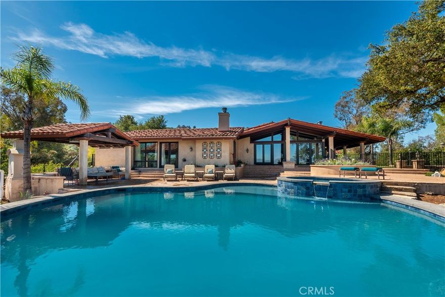 A very rare find! First time on the market in 24 years, this privately gated, nicely upgraded one-story home features panoramic views and a big private lot. Amenities include a spacious chef's kitchen with two islands, freestanding Viking Range and a sunny breakfast room, plus a large great room with vaulted, open beam ceilings, stone fireplace, & walls of glass capturing the expansive views, with an adjoining, open dining room for casual entertaining, and two private offices. The big primary suite includes a fireplace, stone bath with walk-in shower & soaking tub, dual vanities, and a large walk-in closet. There is also an adjoining room (second office) that could be an additional large walk-in closet if desired. Additional amenities include wood floors, stone countertops and big picture windows that fill the home with natural light. The lushly landscaped grounds include a superb, just remodeled, infinity edge swimmers pool with spa, two covered patios, full barbecue center with refrigerator, stone countertops & seating, outdoor fireplace, and beautiful mature oak trees. With a prime location near several public and private schools, just minutes from Calabasas Park Lake and The Commons shopping center, this custom home has much to offer.