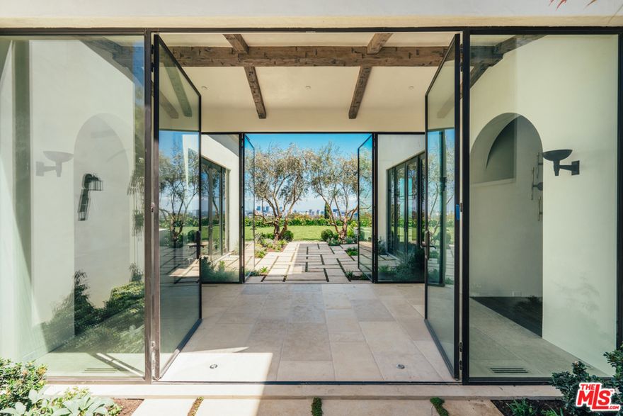 NEW CONSTRUCTION in guard-gated Brentwood Circle on nearly 2 acres with 280-degree city & ocean views. A 200 square foot gated drive takes you to this young and hip Mediterranean designed by architect William Hefner with interiors by celebrity designer Estee Stanley. The formal entry with walls of glass flows to a sprawling lawn with expansive views. The living room has 18 ft. beamed ceilings and a dead-on view of Century City. A formal dining room with coffered ceilings opens to a large stone terrace. The kitchen features a large center island, book-matched marble walls, rustic oak cabinetry, and Bluestar appliances. The family room flows into a screened-in loggia with a limestone fireplace overlooking the pool. The Brass bar has an 800 bottle wine cellar. The master suite dazzles with city & ocean views, 2 walk-ins and a fabulous bath. The upstairs family room leads you to the oversized screening room.