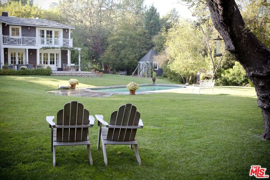 Nestled on a tranquil lane in prestigious Fryman Canyon, this classic Hamptons residence is on a breathtaking, flat, almost one-acre lot, and is the home of an internationally recognized and widely published designer. It has been featured in design magazines across the country. The property is double gated and has a very large motor court. Its elegant two-story facade leads to interiors with stunning finishes, hardwood floors, spectacular millwork, and lovely public rooms. The cook's kitchen (with a very large butler's pantry), cozy breakfast room and seating area open through French doors to the truly fabulous yard, pool and gardens. Upstairs, there are a large and luxurious primary suite, two large en-suite bedrooms, and a family room for studying, a kid's play area, or just hanging out! Outside, set perfectly in the enormous grassy yard, is the large, beautiful swimmer's pool. There is a huge terrace with an outdoor fireplace, seating area and dining area; a lighted pickleball court/sports court and two accessory buildings, which provide flexible space for a home office, gym, or yoga studio. There is also a fantastic kitchen garden for growing fresh fruits and vegetables. Surrounded by mature trees and tall hedges, this home offers a very private and serene retreat just moments from the park, hiking trails, and the fantastic shopping and restaurants of Studio City. This estate is perfect for those seeking a great location, stylish luxury, privacy and security. [$29,500 for an 18-month or longer lease term. $35,000 for a one-year lease.]