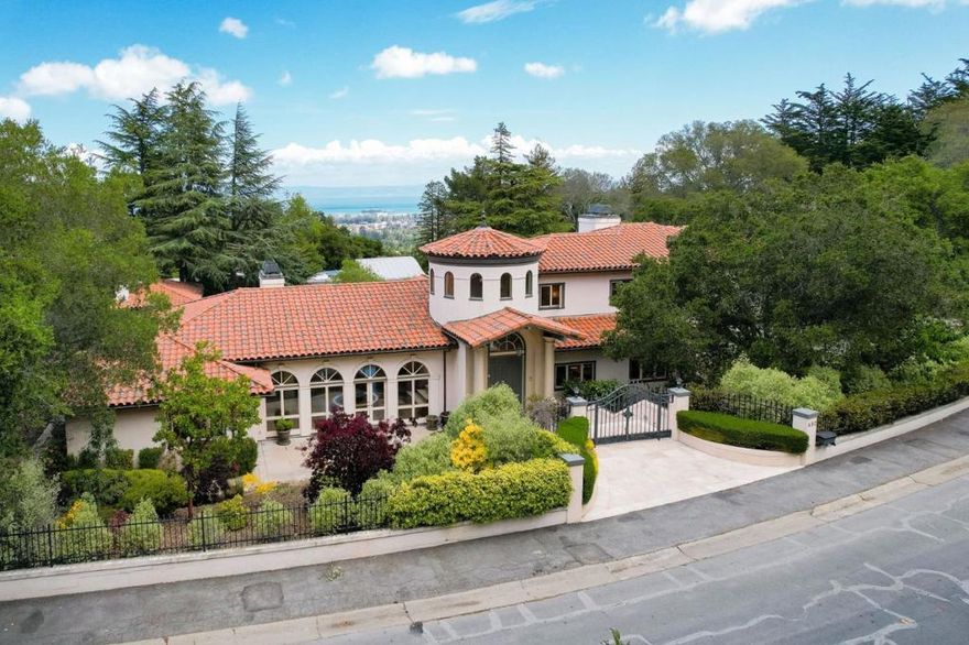 This Mediterranean-style home, with its circular tower foyer, is on a large 0.63 acre+/- corner lot in the Carolands neighborhood of Hillsborough. It offers hardwood floors, recessed lighting, and exposed beam & plank high ceilings throughout. The light-filled living room with arched windows, and French doors, is completed by a manorial fireplace. An open arched doorway leads to a dining room with French doors to the patio and lawn and a spectacular crystal chandelier. The renovated kitchen offers ample storage and abundant counter space, a center island with a breakfast bar, and high-end appliances. You will find a fireplace & a wet bar in the family room. The large master bedroom suite has a fireplace, French doors to the backyard, and a bathroom with two walk-in closets. All the bedrooms are sizable, en-suite, and have ample closet space. To round out this estate are landscaped gardens, patios, a tennis court, and a guest house with a fireplace, a bathroom, and a kitchenette.