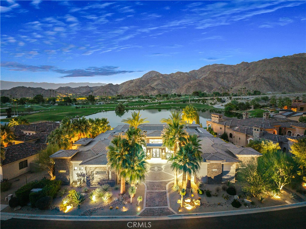 Set on one of the most exclusive vantage points in Ironwood Country Club, this residence captures the true essence of desert serenity. Walls of glass frame uninterrupted vistas across a reflecting lake, the rolling fairways of the two championship courses and to the rugged ridgelines of the Santa Rosa and Chocolate Mountains. At night, tranquility reigns with star filled skies, the radiant hush of the desert, and glowing panoramas that create a natural masterpiece. 
The home spans 6,265 square feet across a private 19,600-square foot lot, designed with a modern, organic, desert centric architecture that blends seamlessly with its natural surroundings. An elegant motor court, framed by palms, water features, and desert landscape welcomes you home. Inside, refined living spaces and walls of glass with 14 foot ceilings open to breathtaking views at every turn. A modern, entertaining kitchen with seating for many, a butler’s pantry with coffee bar, a mountain view dining room, a 1,500-bottle wine room, a private viewing room with huge pivot doors, and a gym, all elevate your everyday living. Each of the four ensuite bedrooms offers its own retreat, including a luxurious private casita with a spa-inspired bath with waterfall shower. The primary suite enjoys exceptional views, two walk-in closets, fireplace, sitting area, and direct access to the pool and spa—perfect for savoring desert nights in solitude.
Ironwood Country Club is a private, member-owned community cradled by the Santa Rosa and San Jacinto Mountains National Monuments. Just moments from El Paseo yet worlds away in ambiance, this rare offering combines natural beauty, ultimate privacy, and a lifestyle defined by peace, exclusivity, and awe-inspiring desert landscapes.