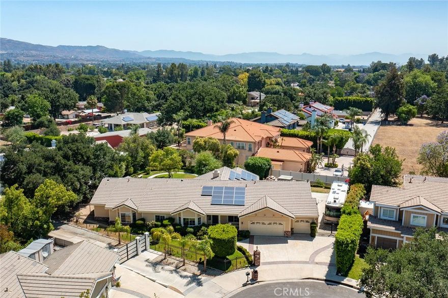 Sprawling single story upgraded estate privately situated at the very end of a quiet cul-de-sac of only 5 homes in one of the most desirable neighborhoods in Chatsworth. Located on an impressive 18,000+ SF flat lot, the property features superb curb appeal with nicely landscaped front yard, 3-car garage with large finished attic and built-in storage, & additional extra wide gated driveway perfect for RV/boat/extra parking for large gatherings. A covered front porch greets you before stepping inside the double door entry. The grand foyer opens to both a formal living room with vaulted ceiling as well as a separate formal dining room with tray ceiling, open shelves, & real hardwood flooring found throughout. The stunning completely remodeled open kitchen boasts gorgeous quartzite stone counters, center island with breakfast bar seating, stainless Cafe appliances including double ovens & 6-burner stove with pot filler, & walk-in pantry with built-in storage & pullouts. The kitchen opens to a separate family room with soaring wood beamed vaulted ceiling & stone fireplace. An additional sunlit bonus room located off the family room features wall-to-wall picture windows, two sets of glass sliders that open to the yard, & wood beamed vaulted ceiling. There are 5 spacious bedrooms including the primary suite featuring high vaulted ceiling, walk-in closet with additional wardrobe closet, & private en-suite upgraded bathroom with dual sinks, quartz counters, bath tub, walk-in shower, & separate toilet room. Two of the secondary bedrooms are massive suites, each with walk-in closets that share an oversized bathroom with dual vanities, tub, shower & built-in linen storage. The 4th bedroom has an en-suite bathroom with dual sinks, tub & shower. The 5th bedroom is located on its own wing of the house ideal for guests with access to its own upgraded bathroom. Additional living spaces include craft room/office, laundry room, & guest powder bathroom. The incredible park-like backyard is an entertainer’s dream featuring large grass lawns with walking path, covered patio with built-in heaters & fan, BBQ center with two grills & sink, above ground spa, & numerous fruit trees including grapefruit, Meyer lemon, blood orange, & plum to name a few. Huge energy savings with completely paid for solar panels. Located adjacent to horse trails, hiking, parks, dining/shopping at the Westfield Mall/Village, & easy access to the 118 freeway. Don’t miss this spectacular offering!