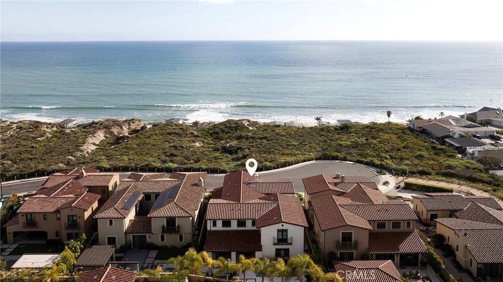 From the historic San Clemente Pier to Dana Point’s sculpted Headlands and the distant silhouettes of Catalina Island, sweeping panoramic views of the Pacific form the ever-changing backdrop to this custom-caliber residence—an elevated offering within the Azure Viewpoint Collection at Sea Summit in San Clemente. Ideally positioned on a single-loaded cul-de-sac framed by protected coastal bluffs, canyon trails, and the raw beauty of preserved open space, the Mediterranean-inspired home welcomes with a covered front patio and fireplace, extending into a sun-drenched ocean-view terrace wrapped in curated hardscaping and lush landscape design. Inside, an expanded floorplan of approximately 4,880 square feet unfolds with quiet grandeur—offering four ensuite bedrooms and four-and-one-half baths, including a refined main-level suite. Soaring ceilings, wide passages, and disappearing walls of glass create a seamless dialogue between indoors and out, with custom built-ins framing the great room’s fireplace and carrying into a dining room that connects effortlessly to both the backyard and an exquisitely appointed kitchen. The kitchen itself is magazine-worthy: a generous quartz island with seating for six, white Shaker cabinetry, artisan tilework, dual pantries—including a walk-in with integrated beverage station—and professional-grade appliances by Sub-Zero, Wolf, and Asko. A dramatic staircase, anchored by a custom desk niche, leads to a sunlit landing, versatile bonus room, and a serene primary suite where a covered balcony captures the horizon. The suite offers a retreat-like sitting area, boutique walk-in closet with direct laundry access, and a spa-like bath with freestanding tub, dual-entry shower, and uninterrupted views of whitewater and sky. Outside, a private loggia, cascading spa, open-air fireplace, and built-in BBQ kitchen complete the home’s outdoor experience—crafted for unforgettable entertaining. Built by acclaimed luxury builder Taylor Morrison, this residence enjoys access to the exclusive Summit Club, a 21,000-square-foot coastal haven with ocean-view pool, spa, fitness center, and entertaining lounge. The Sea Summit lifestyle also includes award-winning schools, access to trails and beaches, and proximity to the shops and dining of the Outlets at San Clemente.