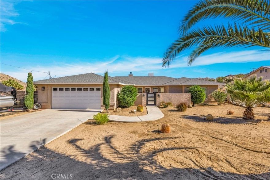 Welcome to 8367 Elk Trl, a beautiful 3 bedroom 2 bath Horse Property located in the highly desirable Juniper Terrace neighborhood of Yucca Valley. This wonderfully maintained property includes an additional Corner Lot (APN 0585-542-04) totaling 1 ACRE of Land (fully fenced)! The additional lot is complete with water, a horse corral, round pen and storage shed. When you arrive you'll pass through a charming courtyard & enter into the main living space which boasts high ceilings with recessed lighting, warm wood-like flooring, a lovely wood-burning pellet stove fireplace and the large north facing windows let in an abundance of natural light. This home's modern style and open-concept layout with a split-floor plan is one to be desired. Just off the living room is a formal dining area which flows effortlessly into the well appointed kitchen, complete with all new stainless steel appliances, ample cabinet & storage space, granite countertops and bar seating. The oversized primary bedroom features a spacious seating area which could double as an office space, nursery, or cozy reading corner. The sizable ensuite bathroom features a dual sink vanity, soaking tub, separate walk-in shower and HUGE walk-in closet. Not to mention this home has a convenient indoor laundry room, dual cooling (AC & Evap Cooling), attached finished 2 car garage and Solar to keep costs low year round (buyer to assume solar PPA). Outside you'll be delighted to find a large covered patio, separate fenced in dog run, privacy fencing, double gate for easy access and ample space to entertain or relax around a firepit on a starry desert night. Located close to town, schools, shopping, eateries & more, come take a look & let this home's charming allure do the rest, your new desert home or weekend retreat awaits!