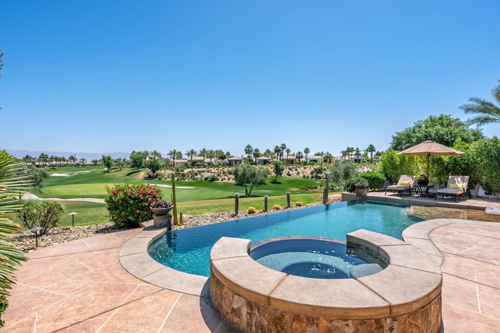 Set against the scenic backdrop of the Rees Jones-designed golf course in Andalusia Country Club, this impressive home captures the essence of desert luxury and effortless indoor-outdoor living. Through a gated, lushly landscaped courtyard, you're welcomed into a refined open-concept floor plan, furnished and artfully designed with two spacious primary suites, each boasting spa-like en-suite bathrooms. A detached casita adds flexibility and charm, featuring two guest bedrooms with separate entrances, a cozy fireplace, and a convenient kitchenette. Inside the main residence, soaring 12-foot Fleetwood sliding glass doors, elegant travertine floors, tailored window treatments, and a grand central kitchen island with a butler's pantry exemplify thoughtful craftsmanship. Outdoors, enjoy resort-style living with a custom infinity-edge pool, elevated spa, ambient fire bowls, and a built-in BBQ island with refrigerator--all overlooking the immaculate 2nd green. Whether you're entertaining or simply unwinding, this home is your sanctuary in the desert. Come live the life you've always imagined!