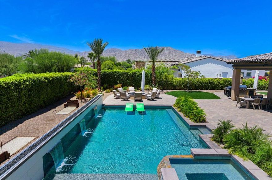 Welcome to Griffin Ranch--a premier, guard-gated community in La Quinta that caters to those who expect nothing less than the best. Perfectly positioned on a premium south-facing lot, this stunning estate is designed for seamless indoor-outdoor living and entertaining, surrounded by panoramic mountain views and lush, maintenance-free landscaping.From the moment you arrive, the attention to detail is undeniable--custom hardscaping, elegant pavers, and mature desert flora set the tone for the luxury lifestyle that awaits.Step outside into a backyard oasis curated for relaxation and recreation alike. Whether you're soaking in the sparkling saltwater pool with Baja shelf, unwinding in the spa, or enjoying friendly competition on the bocce court or horseshoe pit, every element is crafted for comfort and entertainment. Grill poolside in your outdoor kitchen with built-in BBQ, host unforgettable evenings by the open-air firepit, or toast with friends at the custom bar under the covered patio--this home was built for moments that matter.Inside, expansive slide-away glass doors with Phantom exterior screens create a true indoor-outdoor experience, flowing from the elegant great room to the patio beyond. The professionally designed interior is light, airy, and anchored by a chef's kitchen featuring premium stainless steel appliances, a double oven, built-in fridge, oversized island, walk-in pantry, and stylish granite finishes. The open-concept design is complemented by a wet bar with wine cooler, ideal for entertaining guests before a night out--or in.The primary suite offers a tranquil escape with a spa-inspired bath and generous walk-in closet. Three spacious guest bedrooms ensure friends and family feel right at home, while a versatile bonus room can easily flex into a home office, media room, or fifth bedroom. Every space has been elevated with smart home features, custom lighting, designer window treatments, and solar panels for energy efficiency and comfort year-round.A four-car garage offers room for vehicles, golf carts, and storage--an exceptional find in the desert!As a resident of Griffin Ranch, you'll have exclusive access to the community's state-of-the-art clubhouse, offering tennis & pickleball courts, a Jr. Olympic-size pool, fitness and Pilates studios, billiards, BBQ pavilions, dog park, and putting green--a social and active lifestyle built right into your neighborhood.