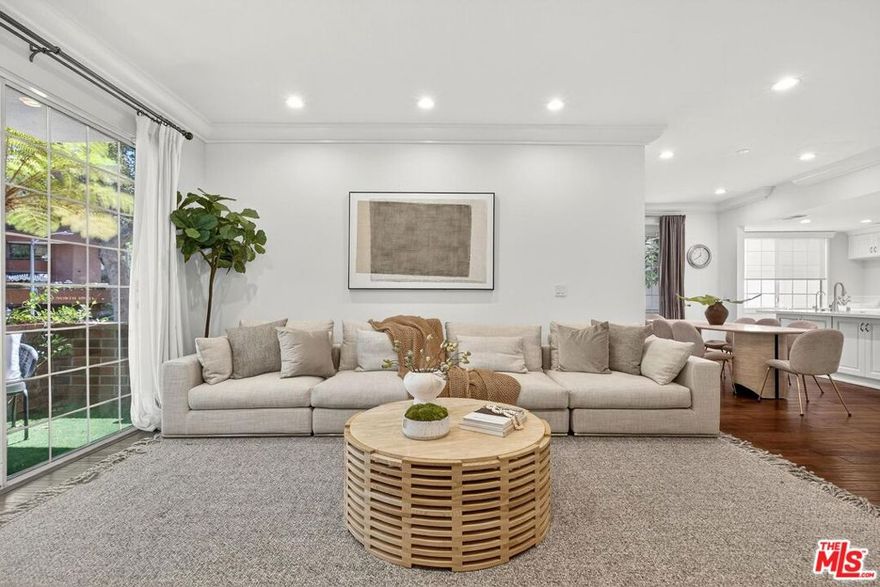 On a peaceful, tree-lined street in prime Beverly Hills, this stylish residence offers the scale and presence of a private home. With an expansive wrap around yard and several sliding doors, enjoy seamless indoor-outdoor living in the heart of the City. The three bedroom unit boasts soaring ceilings, abundant natural light, and a spacious, thoughtfully designed floor plan, offering both grandeur and everyday livability with several luxurious upgrades. Upon entry, a large foyer opens up to a wonderful living, dining room, and office den. Enjoy breakfast on the front balcony or at the charming breakfast nook adjacent to a chef's kitchen that dazzles with sleek quartz finishes and premium stainless steel appliances. The formal dining area sets the stage for memorable family gatherings where you can step outside for some outdoor entertaining. The oversized primary suite with fireplace provides a private sanctuary, featuring a hotel-inspired bath with a Japanese soaking tub, luxurious marble details, and two walk-in closets. Down the hall, a dedicated laundry room and elegantly upgraded powder room are across the hall from two large bedrooms, one ensuite. This spectacular unit comes with dedicated side-by-side gated parking and extra storage space in a subterranean garage for added ease and convenience. Located in a desirable pocket of Beverly Hills, this residence is moments away from world-renowned restaurants, vibrant nightlife, and couture shopping along Rodeo Drive, Robertson Boulevard, and Melrose Avenue. With access to top-rated Beverly Hills Unified schools, this home offers elegance, convenience, and a lifestyle of true prestige.