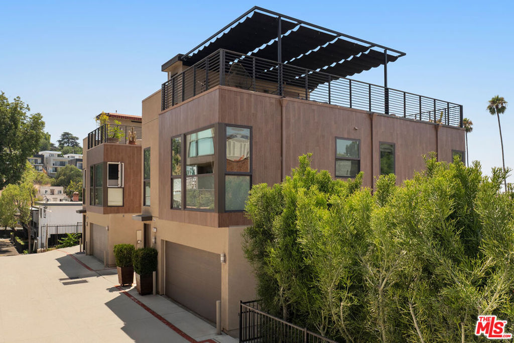 In Echo Park, this modern three-bedroom home delivers elevated design and a massive rooftop deck with stunning vistas. Tucked at the end of a gated community, the residence feels exceptionally private. Expansive layout has seamless flow connecting living, dining, and a stylish kitchen outfitted with quartz-style counters, stainless appliances, and a center island. Large windows bring in the sunlight and frame verdant vistas; hard surface floors run throughout, including marble in all bathrooms. All three bedrooms are ensuite, offering flexibility for guests or work. The downstairs suite opens to a private garden, beautifully landscaped with climbing roses and an olive tree. With a bespoke shade system, the scenic rooftop deck becomes a year-round extension of your living space, a tranquil setting for entertaining and unwinding. Amenities include central AC, laundry, and a two-car garage with EV hookup. The great location puts you near Bacetti, Cookbook, Tilda, Canyon Coffee, and more.