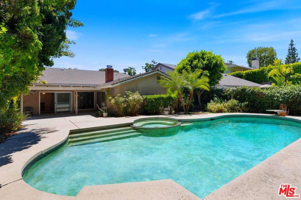 Welcome to 4935 Woodley Ave, a charming 4 bed, 2.5 bath single-story pool home tucked away on a quiet, tree-lined street in prime Encino. This contemporary home sits on a spacious 8,483 sq ft lot and offers timeless character with room to make it your own. Inside this freshly painted house is a dining area and living room with a decorative brick fireplace connecting to a family room area, which is easily convertible to a modern open-concept layout. Kitchen has a stainless steel sink, gas stove, refrigerator and a cozy breakfast nook. There is a large two car garage with direct entry into the house. The bedrooms are located conveniently on one wing of the home, and includes a generous primary suite with ensuite bath, and floor-to-ceiling glass doors that open directly to the expansive backyard. Each bedroom features ceiling fans, natural light, and ample closet storage. Step outside to your private patio with a grand pool and spa, perfect for entertaining or relaxing under the stars. Lush bougainvillea, shade trees, and a welcoming garden entryway, add to the home's appeal. Close to dining and shopping on Ventura Boulevard, with easy access to the Westside, right in the heart of Encino.