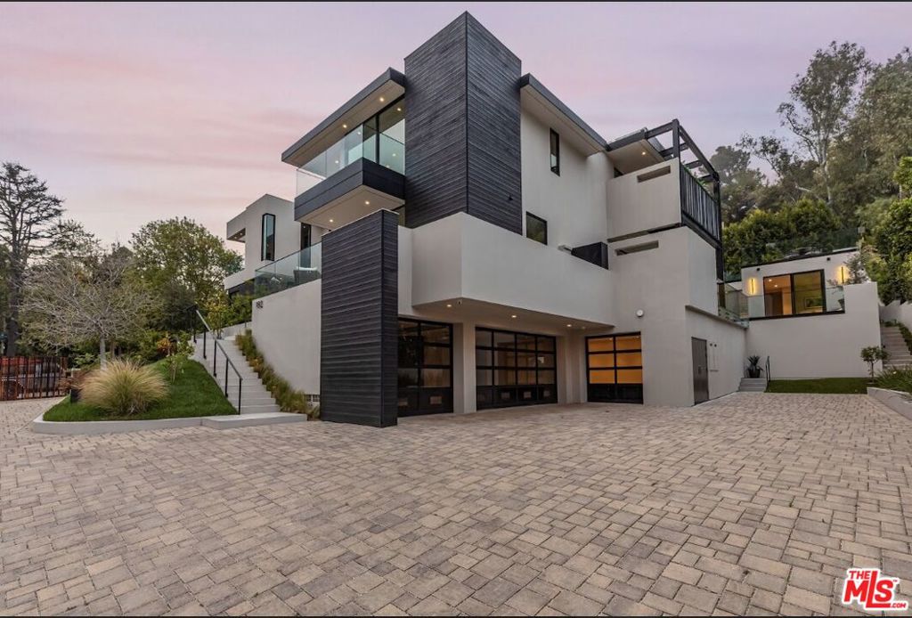 An extraordinary achievement of modern architecture, 982 Stone Canyon Road is a study in precision, light, and form. Designed by acclaimed developer Melanie Marlo, whose visionary work has been showcased on Netflix's Selling Sunset, this Bel Air estate is an extraordinary expression of contemporary luxury. Defined by bold lines and striking geometric interplay on a leveled lot, the residence commands attention from the moment you arrive. A gated motor court sets the stage for the home's seamless integration of structure, privacy and landscape. Inside, vast walls of glass dissolve boundaries between indoors and out, creating a dynamic interplay of light and space. Crisp architectural lines guide the eye through open-plan living and dining areas, where custom finishes and exquisite materials evoke a sense of refined minimalism. The sleek chef's kitchen anchored by an oversized waterfall island features top-tier Gaggenau appliances and seamless cabinetry, reinforcing the home's commitment to both beauty and function. The upper level is an elevated retreat, where four calming bedrooms frame the surrounding canyon further harmonizing the peaceful sounds of the outdoors within the resting spaces. The primary suite, an architectural statement in itself, features a linear marble fireplace, dual boutique-style dressing rooms, and a spa bath with a steam shower and sauna with bespoke finishes that have been meticulously curated to enhance form and flow. The three-level elevator leads directly from the primary suite to lower-level living spaces and the garage. The outdoor landscaping is of utmost significance, where water plays a central role in creating a tranquil, zen-like ambiance with the interiors. Expansive pools and a serene koi pond gracefully wrap around the property, connecting the detached guest suite with the main house. The rhythmic flow of water, paired with meticulously designed landscaping, elevates the property's natural beauty, offering a sanctuary for relaxation and reflection. A rooftop terrace over the guest suite provides additional hours of entertaining or relaxing under canyon stars. At 982 Stone Canyon Road, architecture isn't just aesthetic - it's the cornerstone of a luxury dwelling experience.