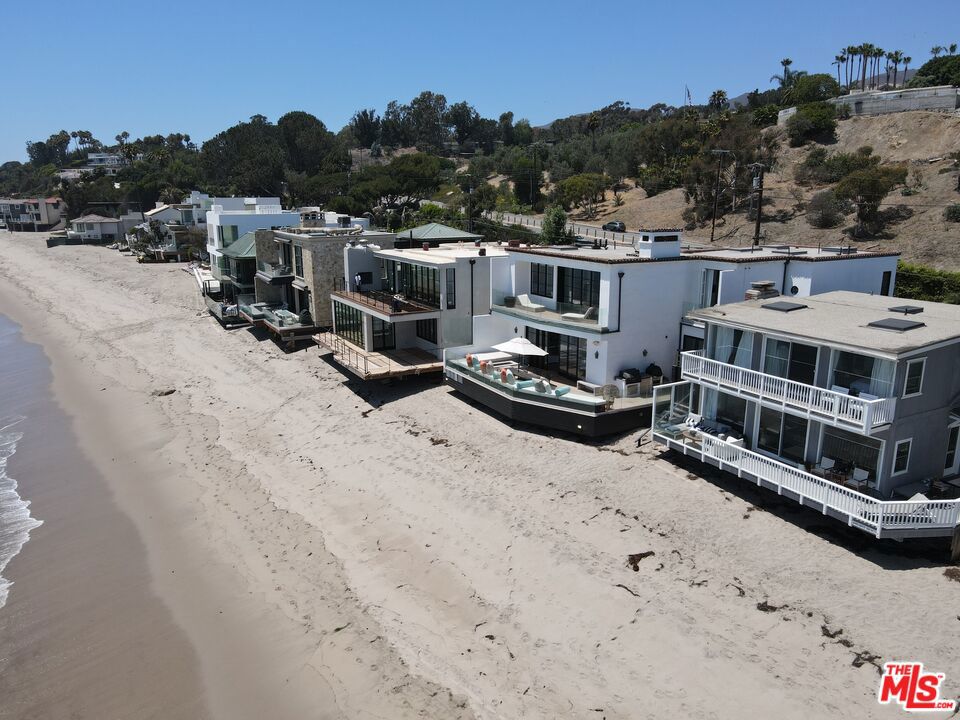 This Spanish contemporary beachfront property is located on the coveted & legendary Escondido beach. It is one of sandiest beaches in Malibu & stretches for miles in the east & west direction. The beach house is positioned facing south, so it captures the breathtaking sunrise over Santa Monica Bay & the sunset over Point Dume. The house was rebuilt in 2016 from the ground up & features a concrete foundation w/ caissons & one of the largest cantilevered decks on Escondido Beach, which sits suspended just feet above the sand allowing seamless private direct beach access. The guest enters the one-of-a-kind beach house via a gated arched entry, which leads to the hardscaped courtyard w/ large spa & mature olive trees. Behind the oversized iron front door reveals the spacious open floor plan w/ high ceilings, recessed lighting & hardwood floors. The kitchen features quartz countertops & high-end appliances, while the living & dining area has a spacious sectional w/ huge tv & plenty of seating for family & guests. Ready for the beach? Then head outside through the floor-to-ceiling sliding glass pocket doors to the expansive oceanfront deck w/ wraparound bench seating, built-in BBQ & private direct beach access. Adjacent to the living area is a cozy media room w/ bar, wine cellar & direct deck access. The second level features two bedrooms w/ Juliet balcony & bunk beds, multiple skylights & a grand oceanfront master suite complete w/ sitting area, balcony & panoramic ocean views from the Queen's Necklace to Point Dume. There is plenty of parking in the two-car garage or designated parking area on the premises & is close proximity to world-class dining, shopping & entertainment. Private membership offering to the Sycamore Tennis Courts available.