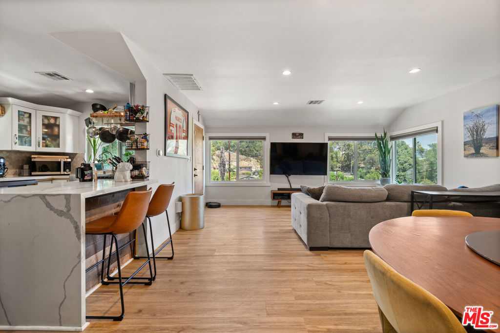 In the hills of Highland Park, this remodeled cottage-style home offers sweeping hillside and mountain views from nearly every room. The main level features two bedrooms with custom closets, light-blocking blinds, and serene outlooks, while the open living and dining areas flow into a bright kitchen with bar seating. The lower level includes a third bedroom with a private entrance, ideal for a home office, studio, gym, and a large additional storage space. Step out to a covered patio and garden that wraps to the front entrance, with mountain views as the backdrop. A backyard terrace above reveals panoramic DTLA views--perfect for extra parking, relaxing, or entertaining. Additional highlights include solar panels for energy efficiency, four parking spaces, and a prime location near hiking trails and just minutes to downtown, blending hillside tranquility with city convenience.