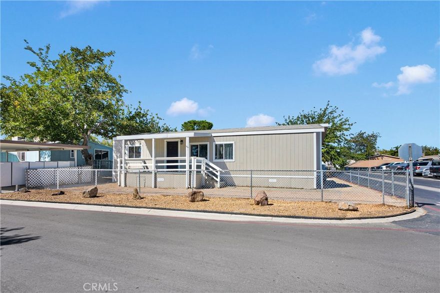 Perfectly located on a desirable corner lot within the community, this beautifully remodeled 3-bedroom, 2-bath home offers both comfort and convenience just steps away from the park office, mailbox, and amenities. From the moment you arrive, the curb appeal is undeniable—freshly painted siding with crisp trim, a gated entry, covered driveway and patio, plus drought-friendly DG landscaping all around for low maintenance living. A backyard shade tree and storage shed complete the outdoor retreat. Step inside and feel the openness of vaulted ceilings and a light-filled floor plan that effortlessly connects the living room and kitchen. The heart of the home shines with brand-new cabinets, white quartz countertops accented with elegant gold veining, stainless steel appliances, and a deep single-basin sink with matte black fixtures. Every detail has been considered: new flooring throughout, fresh baseboards, modern door hardware, and stylish black accents that tie the design together. Both bathrooms are fully upgraded with tiled showers, sleek vanities, designer mirrors, and matte black fixtures for a polished, modern feel. The primary suite features a bold accent wall, spacious walk-in closet, and an en-suite bath designed as a personal retreat. Move-in ready and crafted with care, this home delivers the perfect blend of style, function, and charm. Whether you’re gathering with family, entertaining friends, or simply enjoying the ease of everyday living, this is the home where it all comes together.