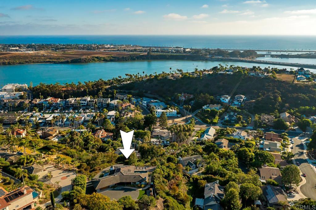 A mid-century modern masterpiece at 1741 Bruce Rd | First Floor Primary Suite | .89 Private Acre lot w/ Iconic Lagoon & Ocean Views | Open concept residence designed around the custom kitchen & great room boasting panoramic Agua Hedionda Lagoon and ocean views at every angle. Gourmet kitchen: Thermador appliances, custom cabinetry, and a breakfast bar, flowing to covered decks for seamless indoor-outdoor living. The primary suite offers a private deck, wood-burning fireplace, and spa-like bath with dual vanities and freestanding tub. Entry-level guest suite, office with built-ins, and lower-level family room with kitchenette and second guest suite. Set on a .89-acre lot with a saltwater pool, spa, and lush landscaping | Owned solar | Minutes to Carlsbad Village, beaches, and I-5