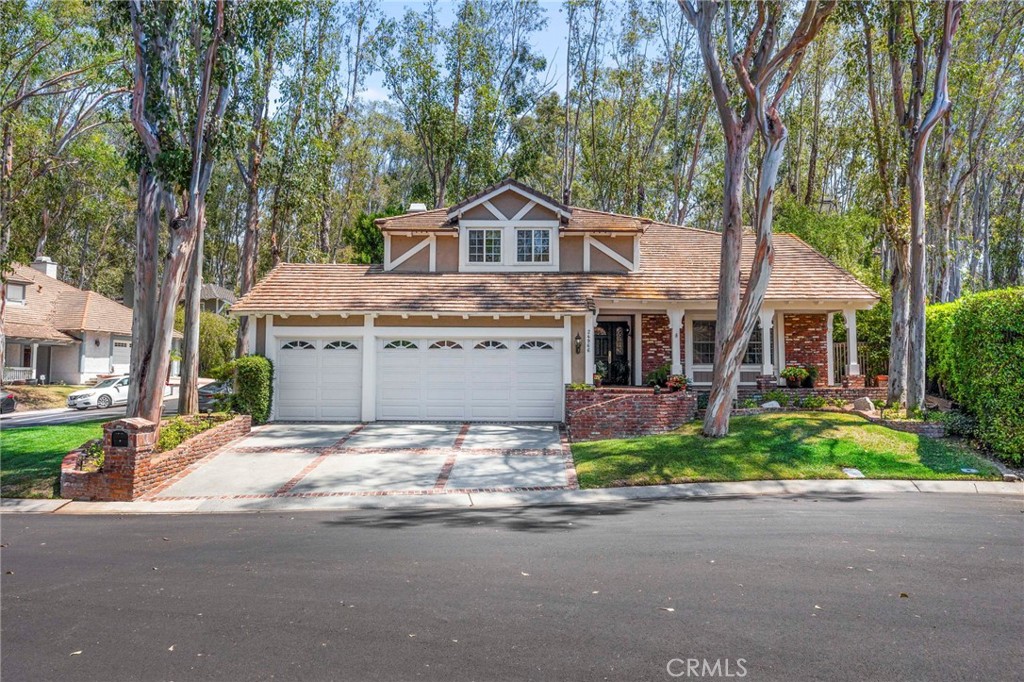 Stunning home, upgraded throughout, located in the community of Whispering Trees on a cul-de-sac, featuring 5 bedrooms, 2.5 bathrooms, gorgeous hardwood floors, updated and remodeled kitchen and bathrooms. Formal living room and dining room with French doors leading to patio. Step down to your separate family room with a beautiful brick fireplace and views to the charming backyard with all its brick detail. Upstairs you will find the primary suite and 4 additional spacious bedrooms, all with ceiling fans. Both remodeled bathrooms have dual sinks. Powder room downstairs also upgraded. Inside laundry, vinyl windows throughout. Close to schools and the resort-like Sun and Sail Club with 4 pools, pickleball, basketball, volleyball, tennis courts, playground, inside workout room with view of the lake, banquet room, locker room and more! Easy access to the 5/405 and toll roads, just a wonderful community.