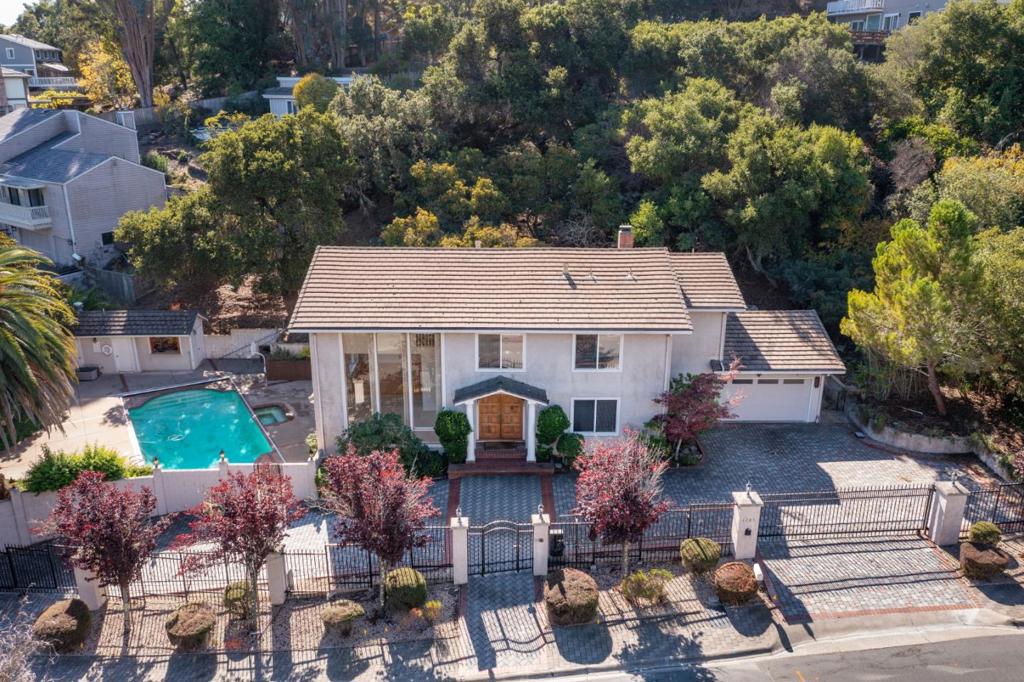 Situated on a commanding .52-acre lot with a gated, circular driveway, this 5BR/3.5BA home offers an amazing, flexible floor plan. The sun-lit main level offers a dramatic step-down living room with towering ceilings and captivating floor-to-ceiling windows, a large formal dining room perfect for grand-scale entertaining, an eat-in-kitchen with adjoining family room with fireplace, a 5th bedroom perfect as an office or au-pair, and a convenient laundry room. The upper level features 4 generously-sized bedrooms, including the lavish primary suite with spa-like marble bathroom. Outside, the resort-inspired grounds boast large entertaining patios, level lawn, a huge pool with spa, and a cabana with full bath. Conveniently located near downtown Burlingame and San Mateo, top-rated schools, and major commute routes.