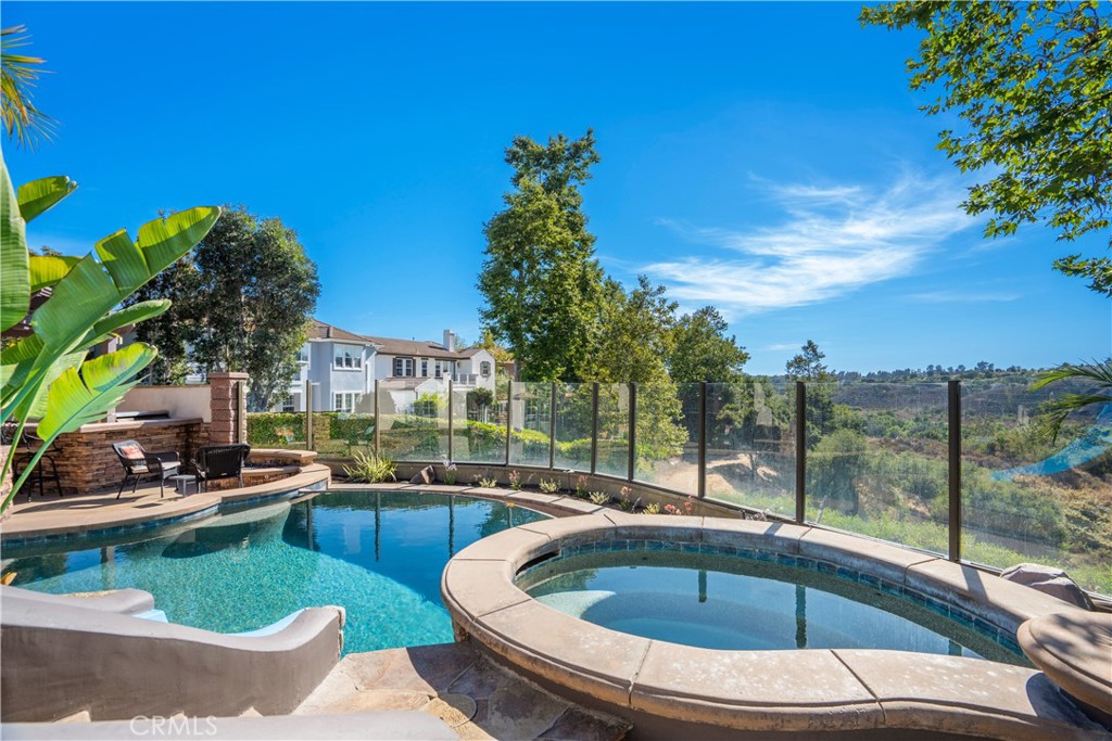 Nestled on one of the most desirable streets in Ladera Ranch, 25 Thalia offers an exceptional blend of privacy, views, and indoor-outdoor living. Set on a peaceful double-ended cul-de-sac and perfectly positioned next to a serene greenbelt, this charming residence enjoys panoramic wooded canyon and valley views. This home is designed for seamless entertaining and everyday enjoyment. A cantina door creates an effortless connection between indoor and outdoor spaces, inviting you to take full advantage of the coastal California lifestyle. The backyard retreat features a spectacular infinity-edge pool, spa, baja shelf and dramatic water slide, with an adjacent outdoor bar seating area perfect for grilling and dining. This stunning home also includes a separate atrium with a second BBQ and additional space for relaxing, ideal for hosting or unwinding in style. The expansive floor plan offers up to six bedrooms, with two bedrooms and a dedicated office on the main level, a large primary suite, plus three additional bedrooms upstairs. (one is currently configured as a large bonus room). At the heart of the home, the gourmet kitchen overlooks the family room, backyard, and courtyard, and features granite countertops, a full backsplash, stainless steel appliances, built-in refrigerator, nook seating, and barstool seating at the island, making it a true command center for the home. Additional highlights include crown molding, custom wood and glass office doors, a stately wood garage door, expansive hardscape, and an open side yard enhancing the sense of space and privacy. A rare opportunity to enjoy an entertainer’s dream in one of Ladera Ranch’s most coveted locations. Oak Knoll’s clubhouse is close by, as well as trails for hiking, biking and jogging. This prime location is also minutes from the Cox Sports Park, shopping centers and award-winning schools.