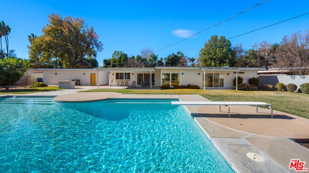 Welcome to this re-imagined Mid-Century Modern house in Woodland Hills located just minutes from the Westfield Mall/Topanga Village and local amenities. This gated 3 bedroom 3 bath home features an open living area with wood-burning fireplace, floor-to-ceiling windows & doors that open up to the spacious back yard complete with large pool, mature fruit trees, expansive garden area & large grassy lawn perfect for entertaining. Enjoy the welcoming dining room, family room, full bath & custom kitchen feat. walnut cabinetry, luxury stainless steel appliances and quartz countertops. The other side of this home has 3 generously sized bedrooms including a gorgeous primary suite w/walk-in closet & bath complete with dual showers, separate bathtub & dual vanities. Additional features include new electrical, new LED lighting, security cameras, 3-car garage & a smart home system that controls the lights, a whole-home sound system, and HVAC, etc. This is a great opportunity to own a mid-century home on a spacious lot.