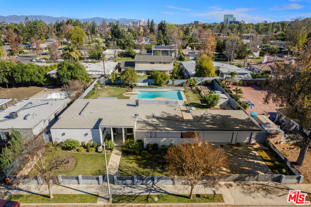 Welcome to this re-imagined Mid-Century Modern house in Woodland Hills located just minutes from the Westfield Mall/Topanga Village and local amenities. This gated 3 bedroom 3 bath home features an open living area with wood-burning fireplace, floor-to-ceiling windows & doors that open up to the spacious back yard complete with large pool, mature fruit trees, expansive garden area & large grassy lawn perfect for entertaining. Enjoy the welcoming dining room, family room, full bath & custom kitchen feat. walnut cabinetry, luxury stainless steel appliances and quartz countertops. The other side of this home has 3 generously sized bedrooms including a gorgeous primary suite w/walk-in closet & bath complete with dual showers, separate bathtub & dual vanities. Additional features include new electrical, new LED lighting, security cameras, 3-car garage & a smart home system that controls the lights, a whole-home sound system, and HVAC, etc. This is a great opportunity to own a mid-century home on a spacious lot.