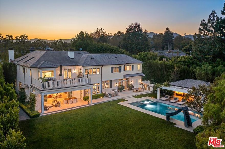 Laden with luxe amenities and incredible design, 1172 Napoli Drive is a gated oasis located next to the prestigious Riviera Country Club. With seven bedrooms, nine bathrooms and an impressive 13,452-square-foot floorplan on over a half-acre, this home beckons a coveted lifestyle of beauty and comfort. Immediately making an impression with a grand facade and lush front yard, the home features a columned front porch, a three-car garage and a motor court. Inside, ceilings soar overhead and a curved staircase greets guests in the foyer. Find a lovely sitting room with box beamed ceilings and bay windows, a formal dining room with a statement chandelier and an enticing family room with a fireplace and a wall of glass that opens to the tranquil outdoor space. Dine al fresco under the covered patio (complete with heaters, a fireplace and a flatscreen), cook a delicious meal in the outdoor kitchen, lounge poolside, soak in the spa or have a splash of fun with the waterslide. Enjoy an expansive lawn, raised garden beds, a gorgeous guesthouse with a kitchenette and bathroom and the privacy created by surrounding ficus trees. The kitchen provides chic blue cabinetry, Miele appliances, marble countertops, a dining area and a long window seat that looks out onto the garden. A butler's pantry adds ease and a secondary family room features gorgeous wallpaper. A perfect work-from-home retreat, the stylish office includes a wall of built-ins and elegant wainscoting. The magnificent primary suite features vaulted ceilings, a fireplace, a spa-like bathroom, an exquisite walk-in closet and a balcony. Additionally, find a wellness room, upstairs lounge, laundry room with four machines, spectacular theater, lower level rec room with a full bar, a temperature-controlled, walk-in wine cellar and a gym. With every detail carefully attended to, experience the height of style and luxury. Your private haven awaits.