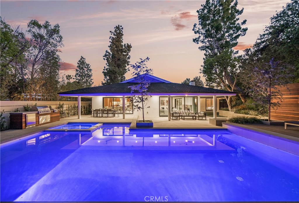 Extremely rare 4,200 SF single level completely reimagined mid-century modern located at the very end of a quiet cul-de-sac in the coveted Royal Oaks neighborhood of Encino. The property sits elevated above the street with long driveway flanked by lush landscaping including a mature olive tree that leads to a motor court and newly built 2-car garage. Step inside to find a sprawling one level open floor plan with soaring ceilings, immaculate attention to detail, and bespoke designer finishes. The grand entry foyer has a guest powder bathroom and opens to an expansive living room with vaulted ceiling, two sets of sliding glass doors that open seamlessly to the backyard for optimal indoor/outdoor flow, custom storage displays, and stone fireplace. The chef’s gourmet kitchen boasts center island, stainless Thermador appliances, custom cabinetry with appliance garage, and separate dining area with glass slider that opens to the yard. The luxurious primary suite has two large walk-in closets with custom built-ins and private bathroom with stone integrated custom vanity, walk-in shower, soaking tub, and separate toilet room. There are four additional well appointed bedroom suites, each one has a private and uniquely designed bathroom. One of the secondary suites is located on a separate wing with its own exterior access ideal for guests or office space. The entertainer’s backyard is extremely private with no neighbors in sight featuring redesigned swimming pool & spa with raised lounging deck, BBQ center, covered patio, and separate lawn space with built-in seating area. Truly private residence with stellar location and quality craftsmanship. Adjacent to top tier dining and shopping with easy freeway and canyon access.
